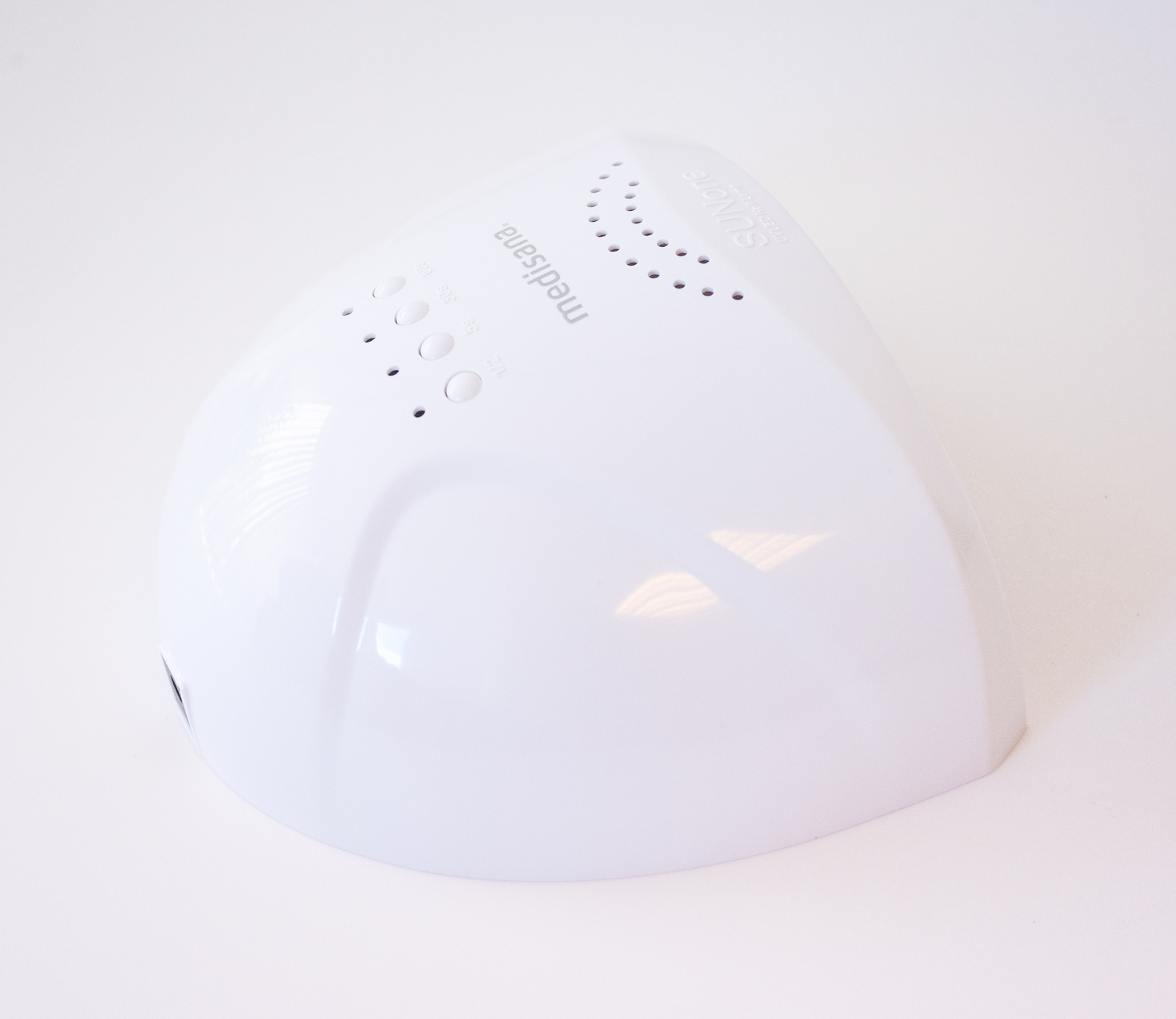 Witte nagellamp met afgeronde bovenkant, knoppen en het woord 'medisana'.