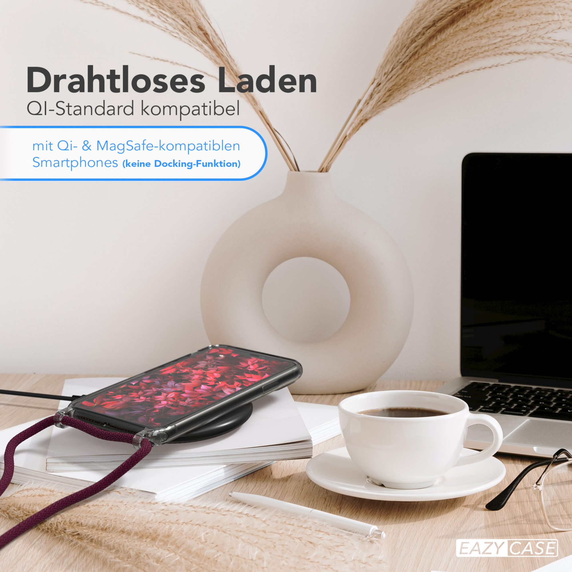 Telefon kabellos laden. Telefon mit weinrotem Gehäuse auf kabellosem Ladegerät. Eine Tasse Kaffee und ein Laptop sind in der Nähe.