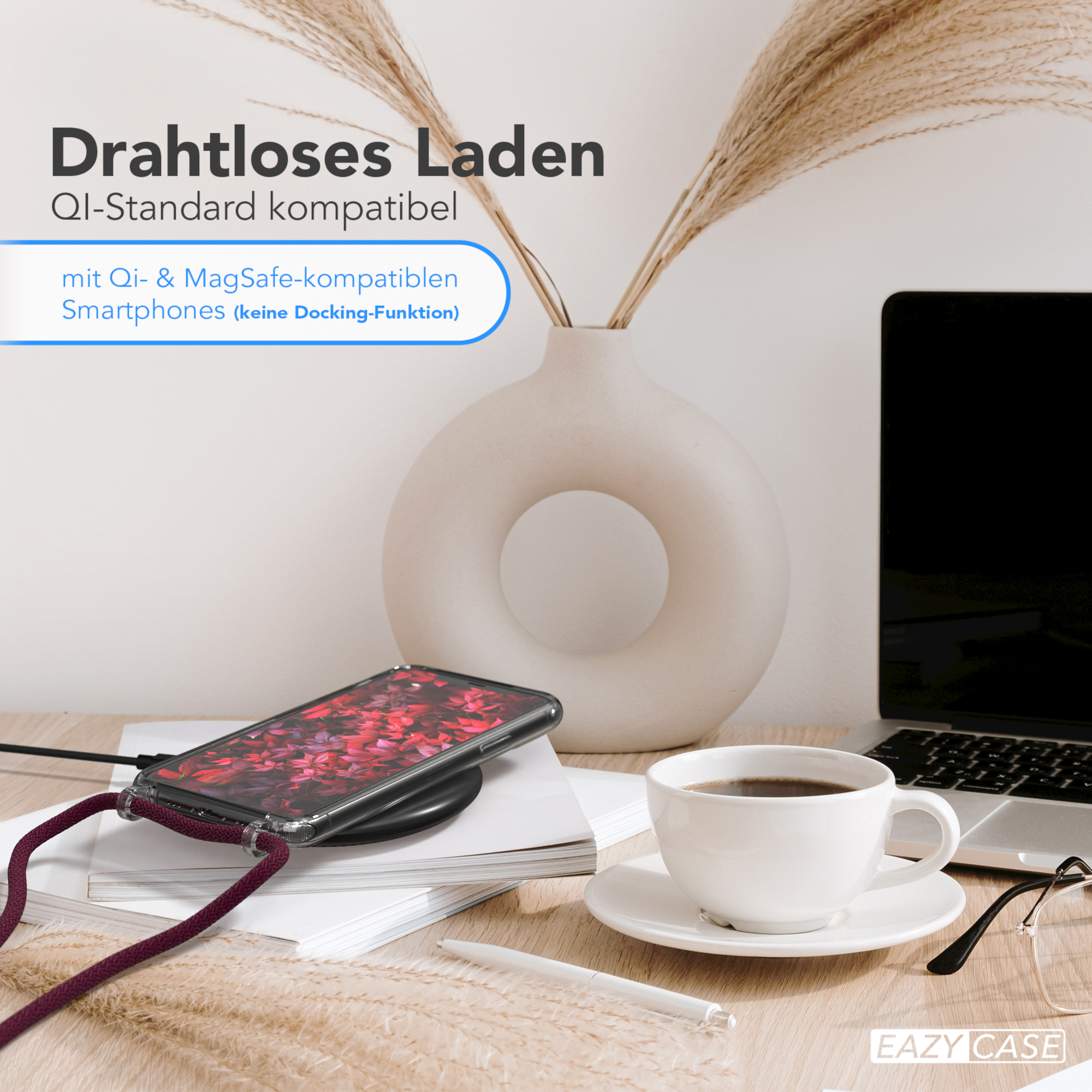 Ein Telefon auf einem kabellosen Ladegerät auf einem Schreibtisch. Es gibt eine Vase, Kaffee und Brille.