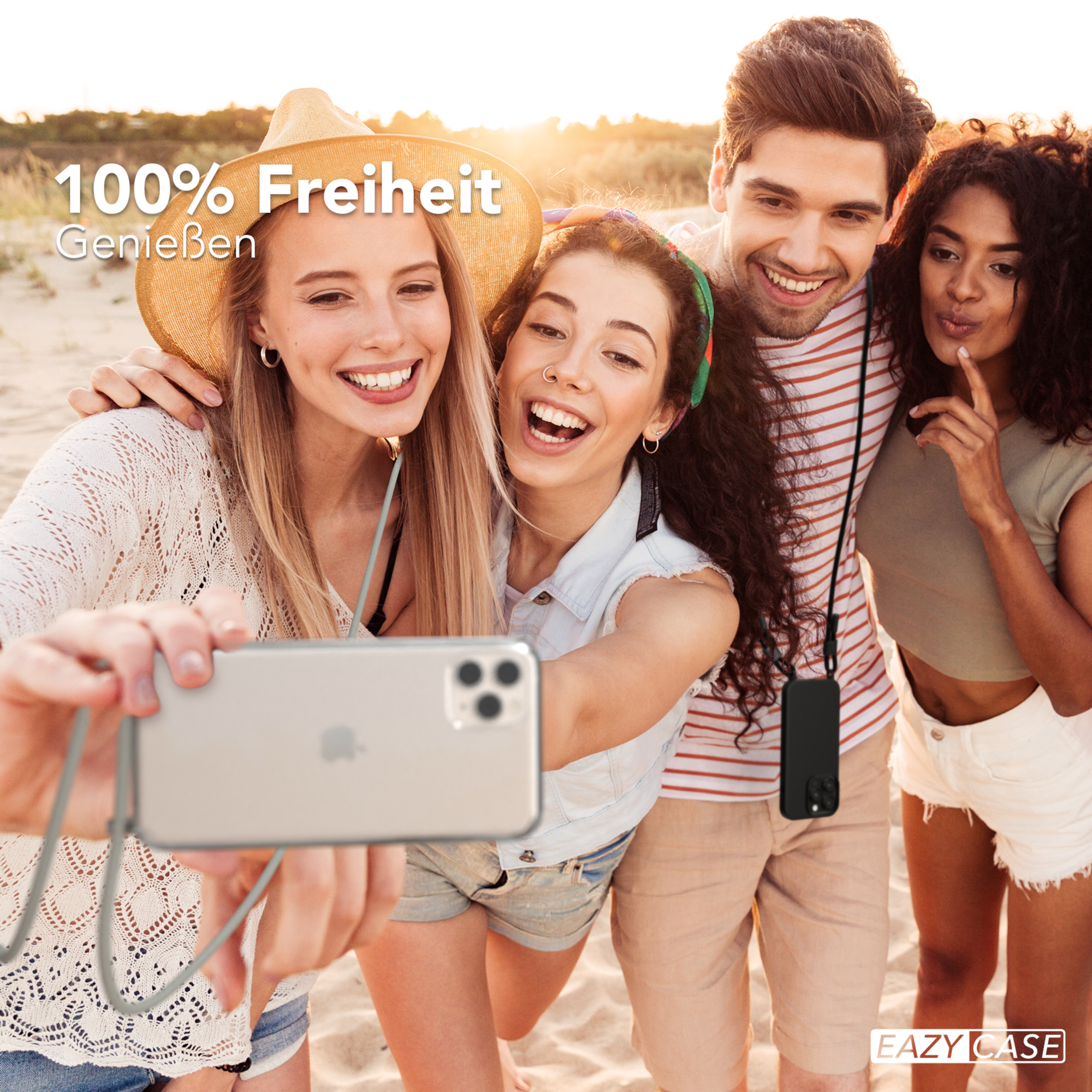 Vier lächelnde Personen machen ein Selfie am Strand, halten ein Telefon.