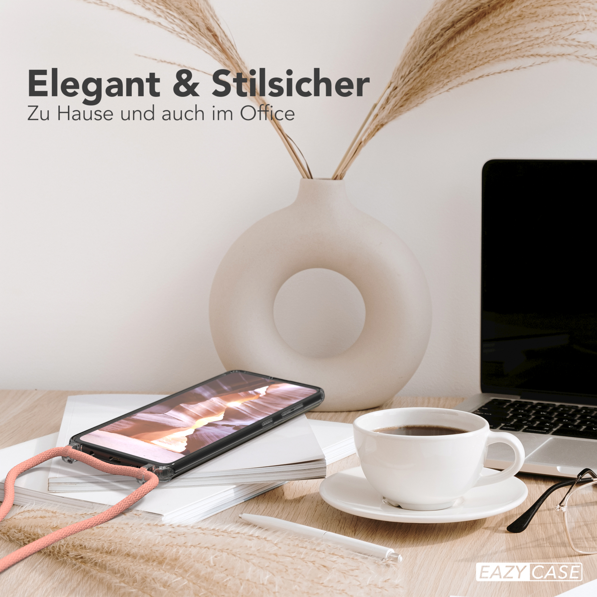 Smartphone in Hülle auf Schreibtisch mit Deko, Laptop im Hintergrund.