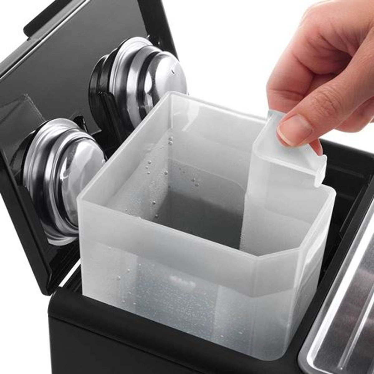 Ręka wyjmuje pojemnik na wodę z czarnego ekspresu do kawy.