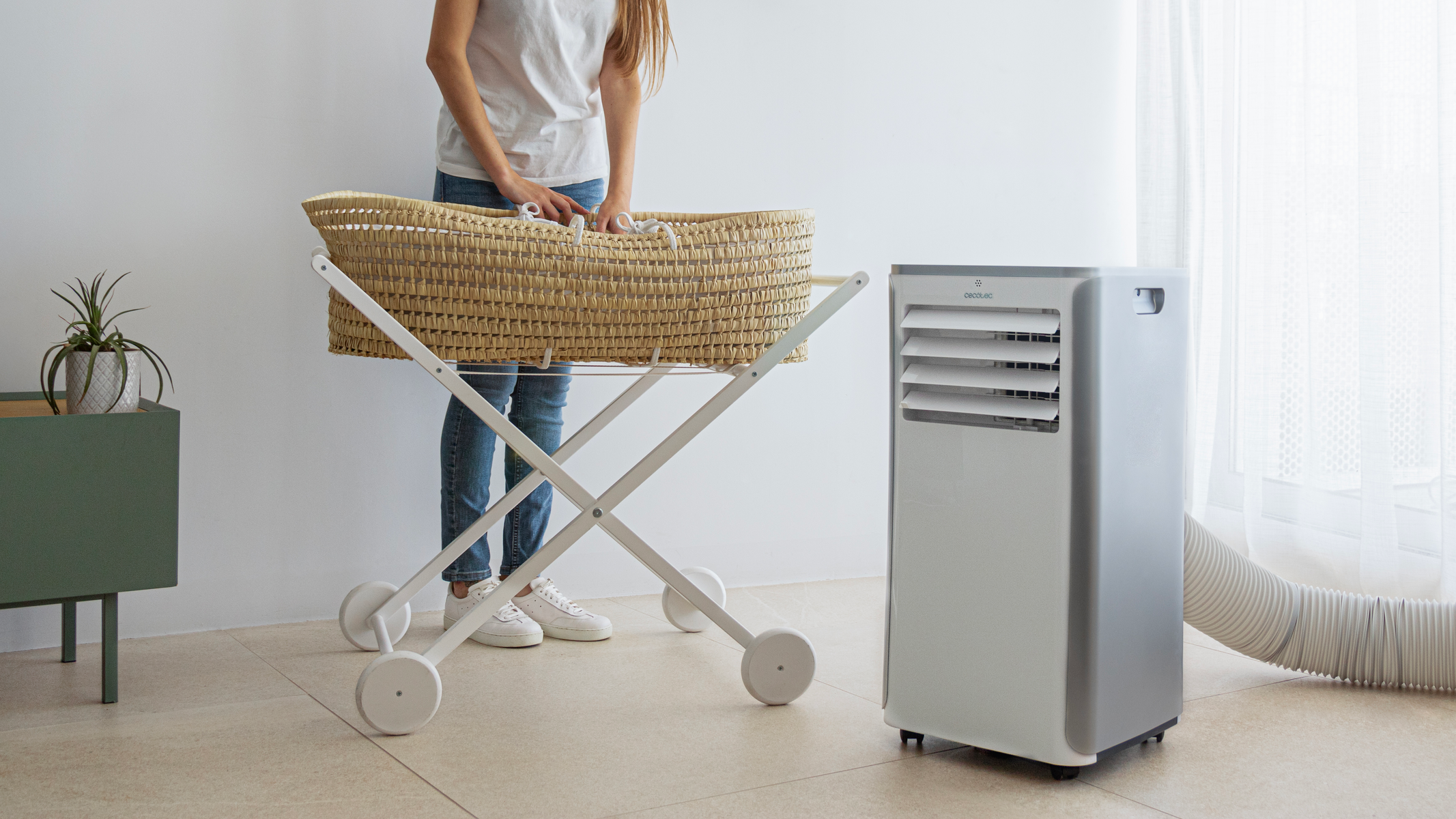Kobieta obok kołyski na kółkach, obok przenośnej chłodziarki powietrza.