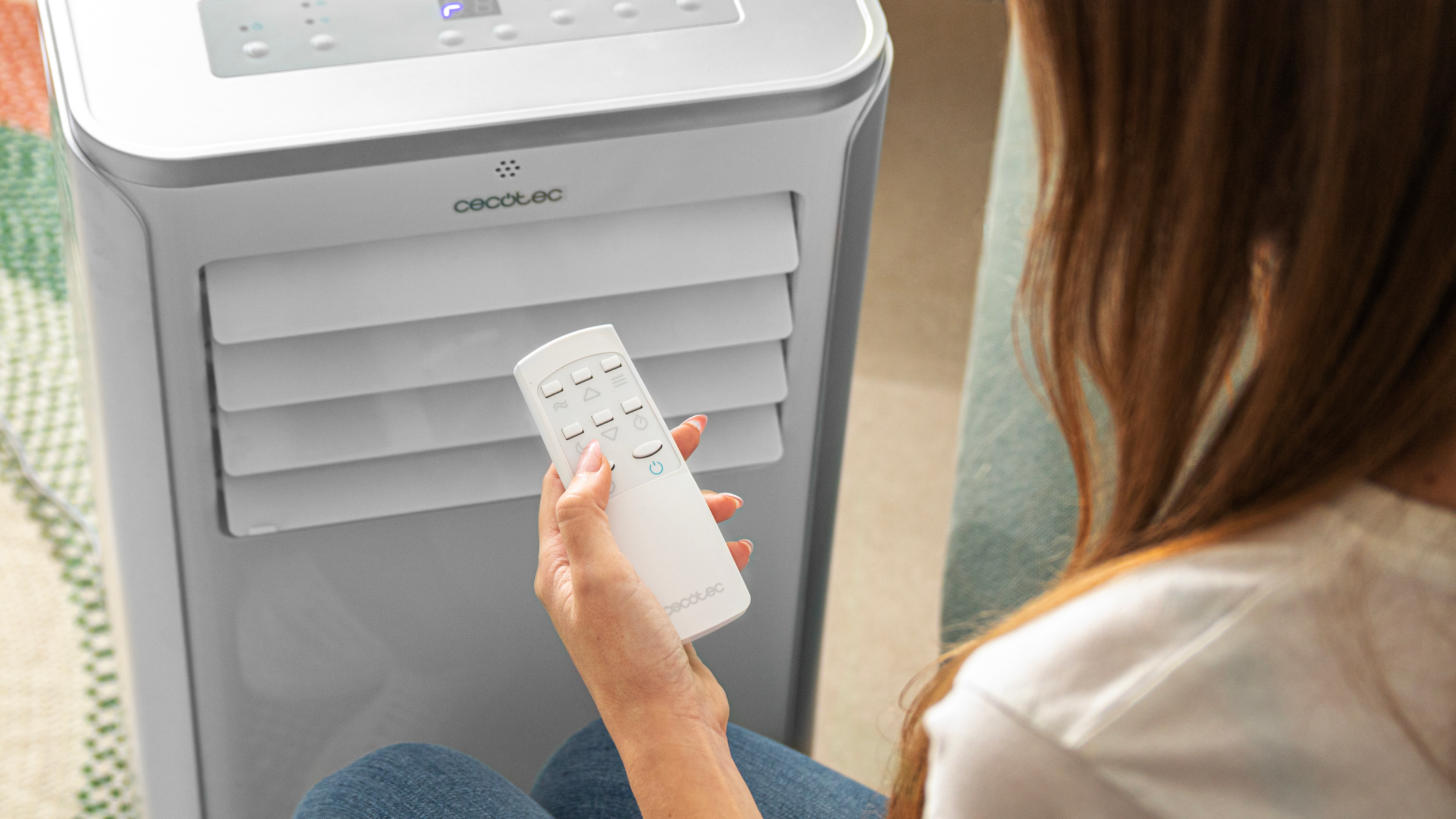 Kobieta trzymająca biały pilot Cecotec przed szarą chłodziarką powietrza Cecotec.