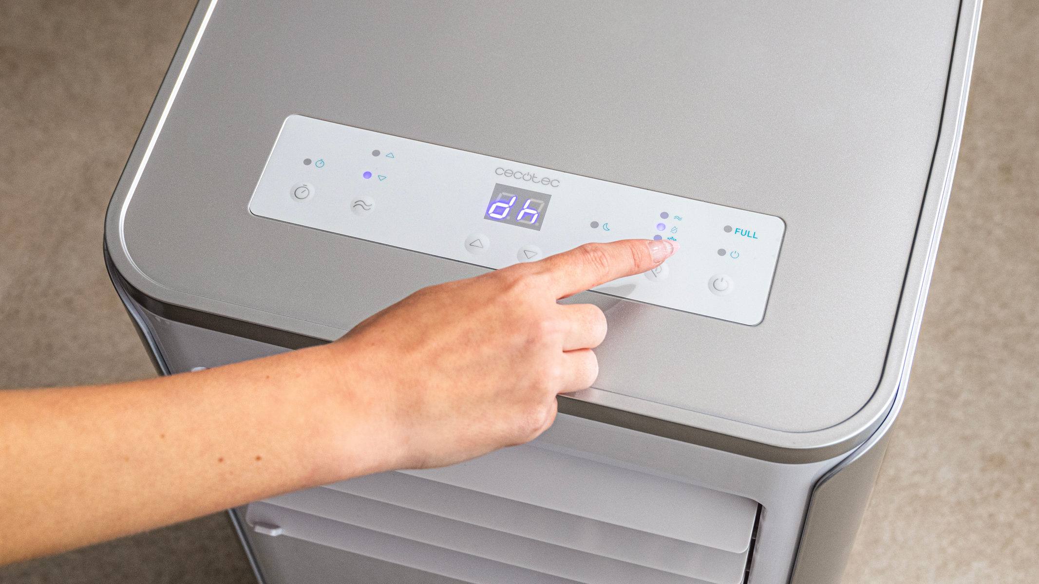 Ręka osoby naciskająca przycisk na srebrnym i białym panelu sterowania chłodziarki.