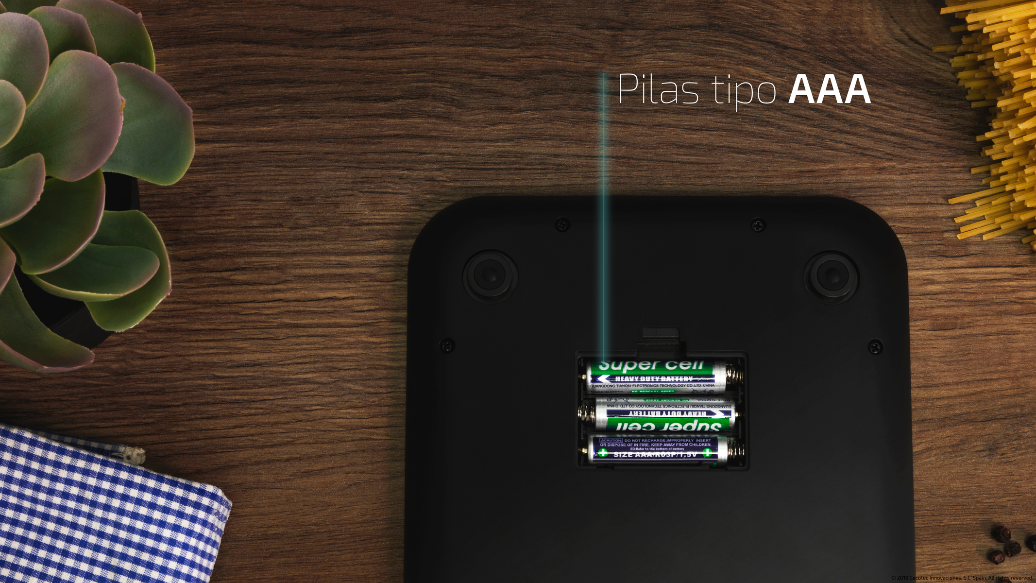 Bilancia con vano batterie aperto. Quattro batterie AAA nello slot. Superficie in legno.