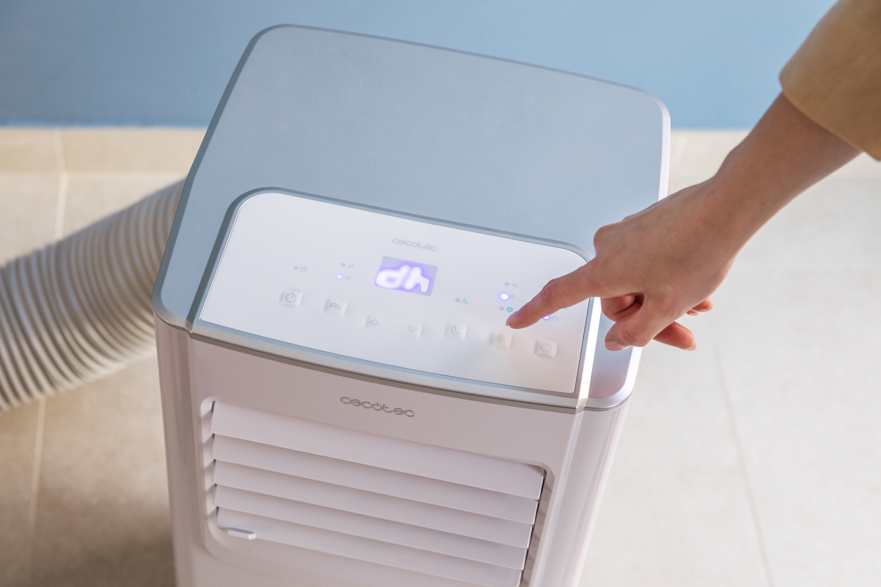 Ręka osoby dotykająca wyświetlacza biało-szarej chłodnicy powietrza. Wyświetla elementy sterujące i ustawienia.