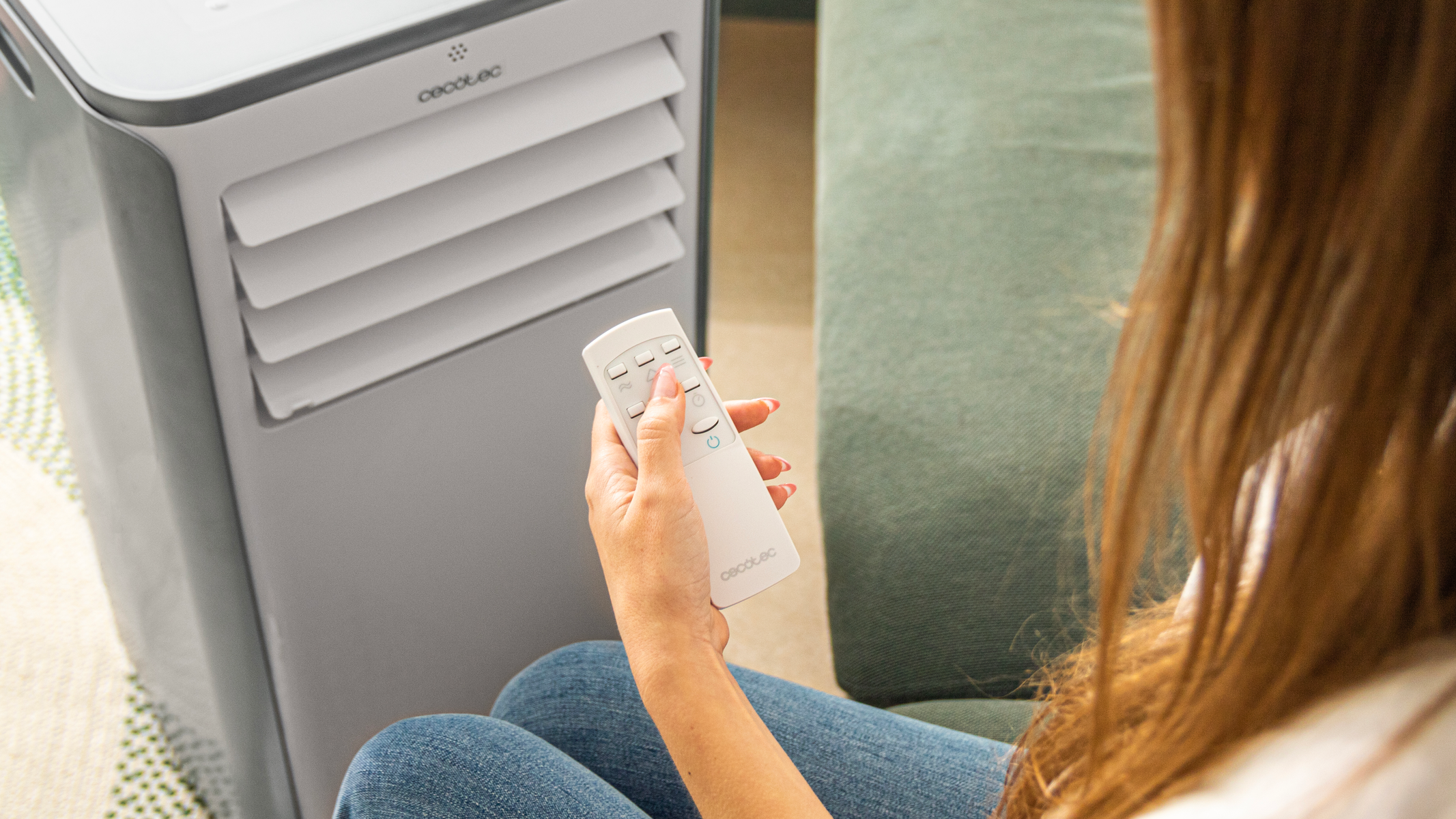 Osoba trzymająca biały pilot wskazujący na szarą chłodziarkę powietrza.