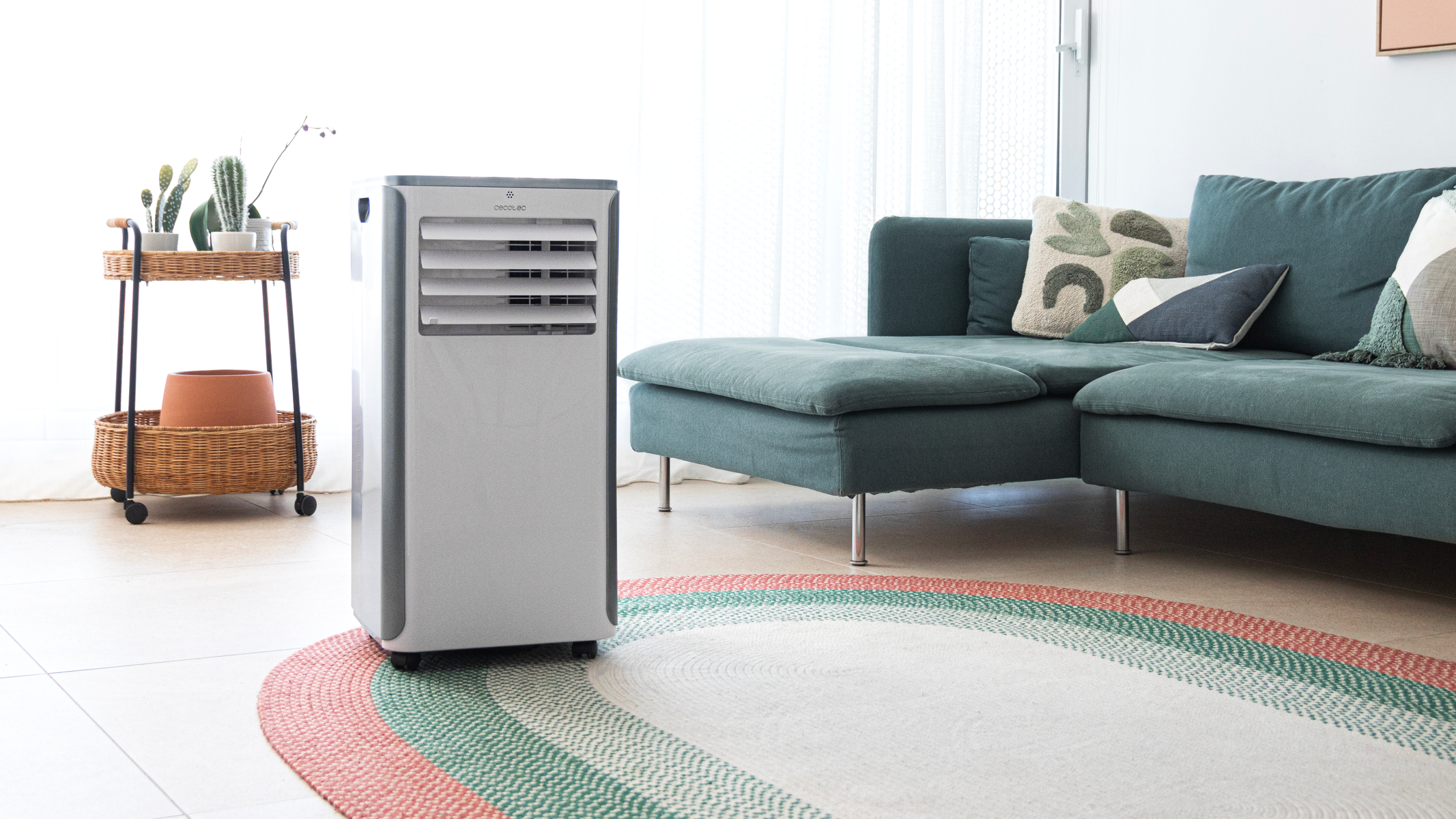 Salon z biało-szarą jednostką klimatyzacji. Widoczna sofa, dywan i elementy dekoracyjne.