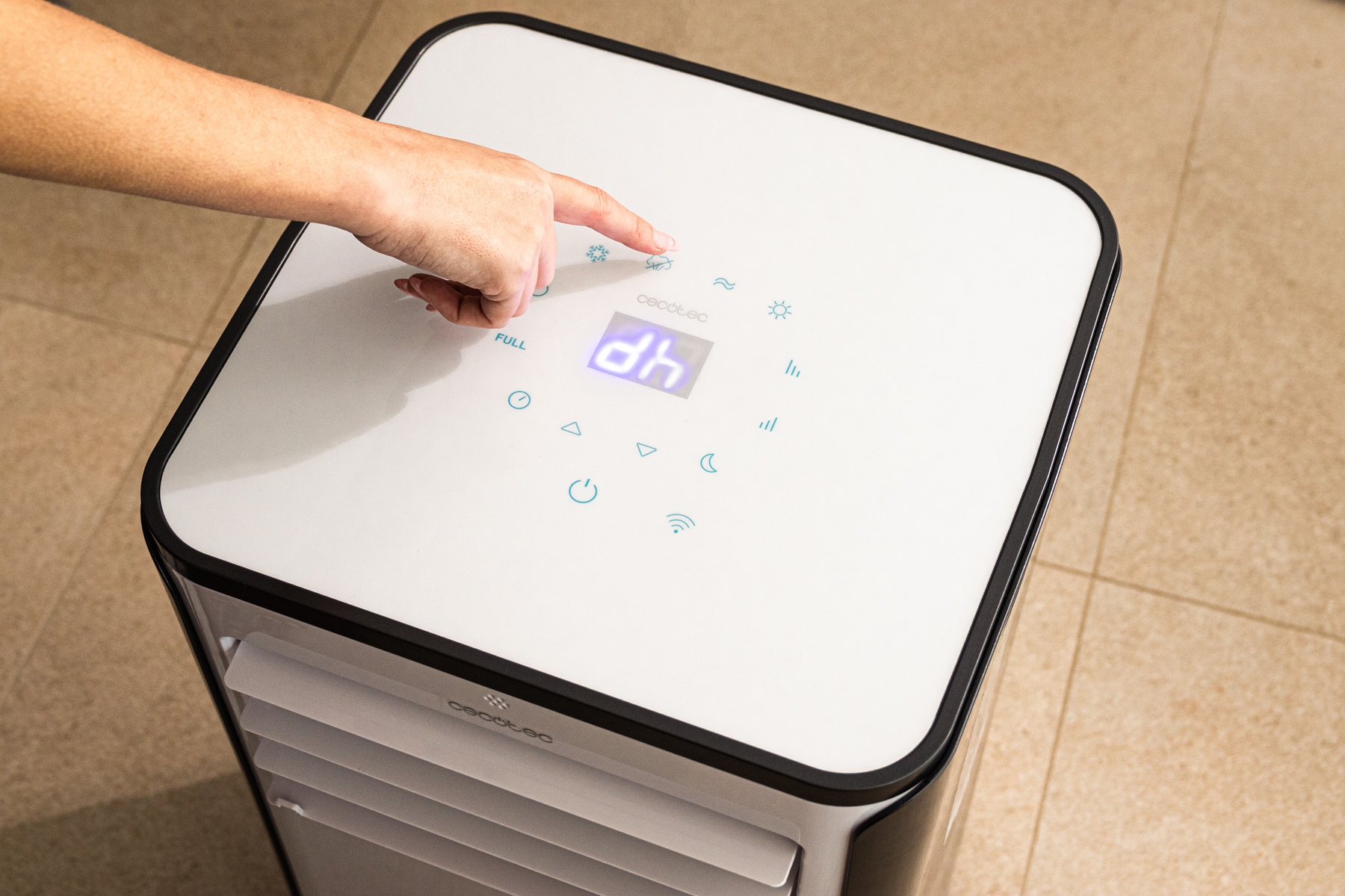 Una mano preme un pulsante su un condizionatore bianco e nero con display digitale.