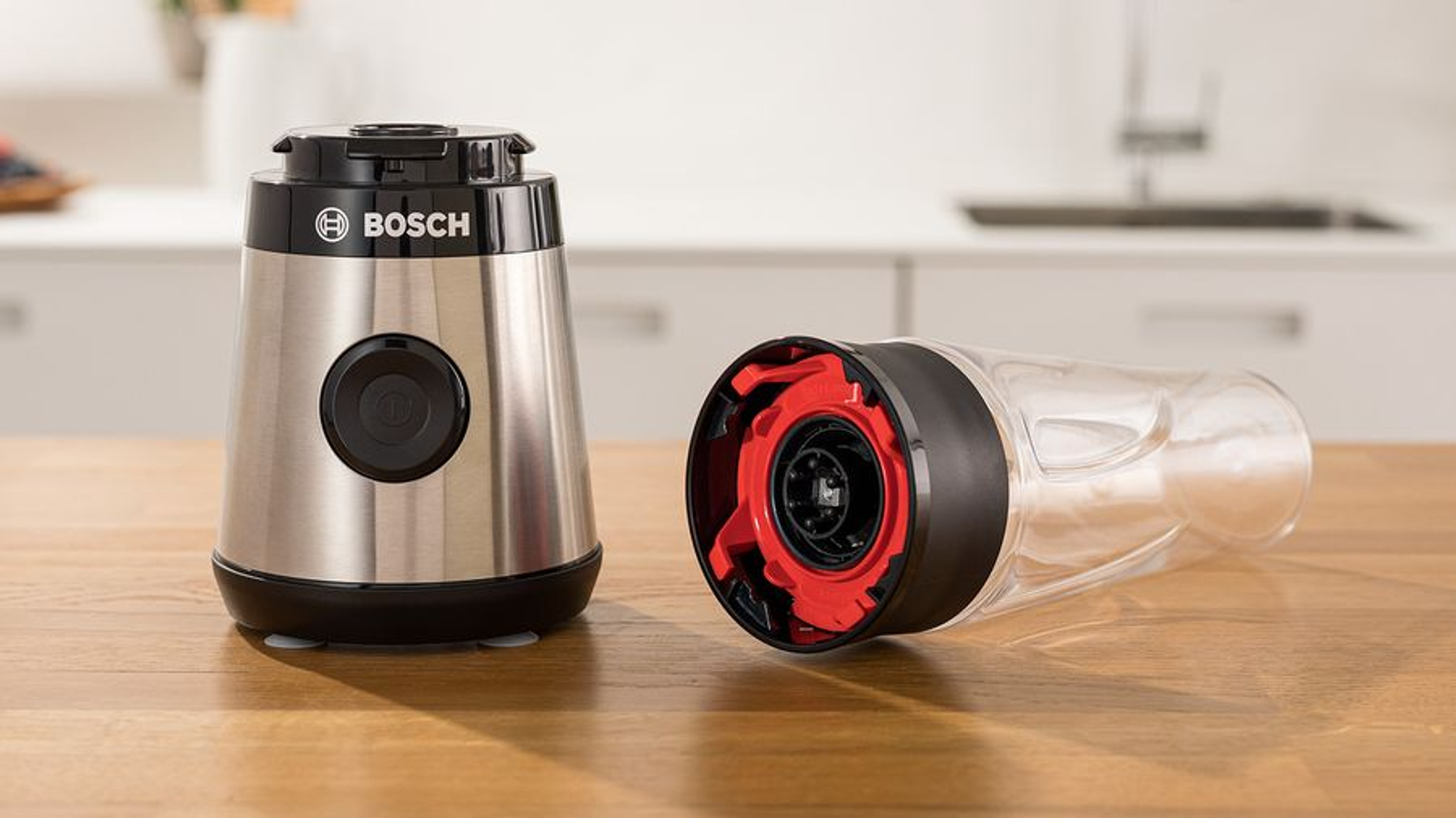 Una licuadora Bosch con dos partes: la base con botón y el recipiente transparente desmontado.