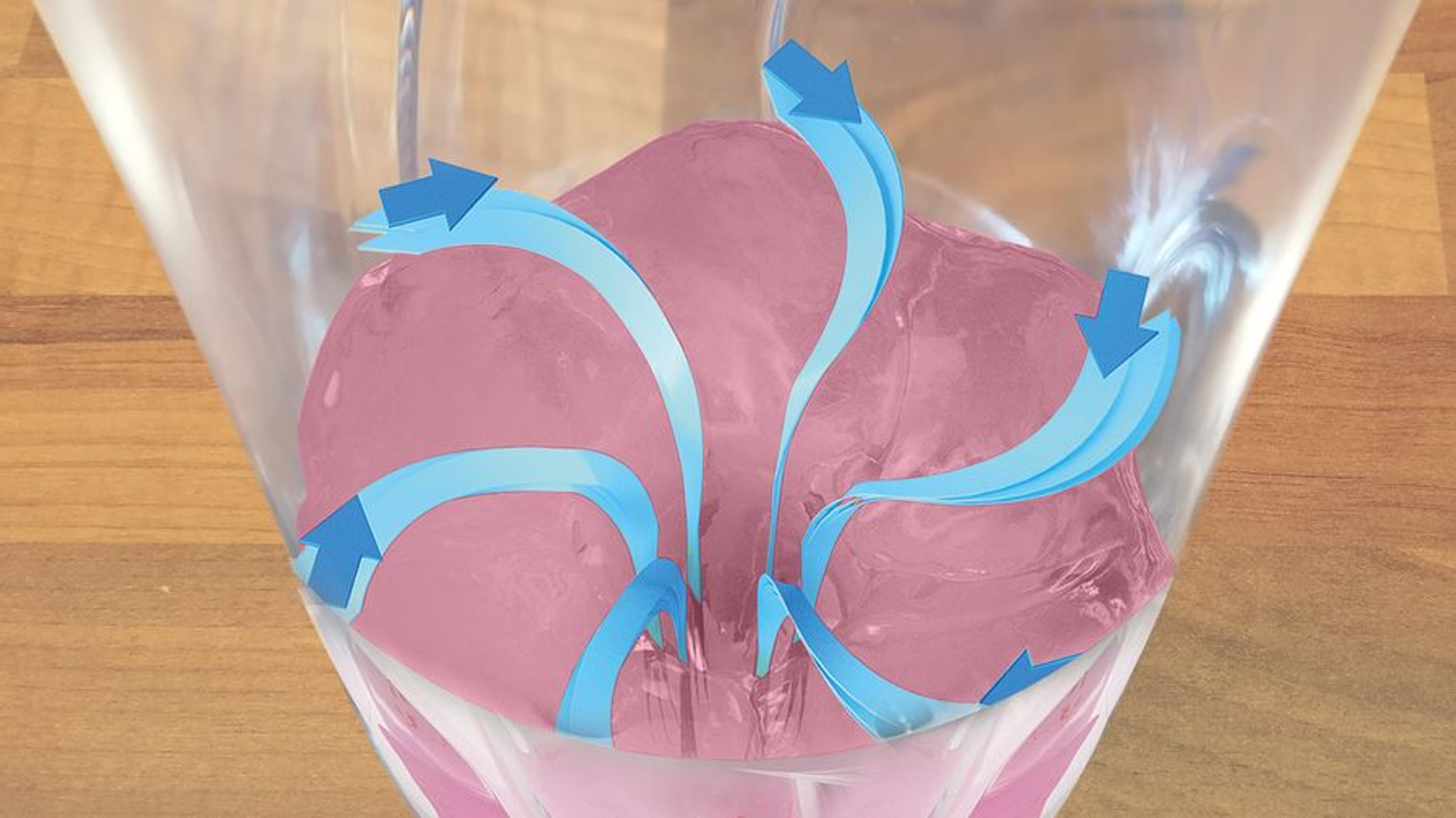 Sustancia rosa en un vaso transparente con flechas azules que indican movimiento de fluido. Fondo de madera.