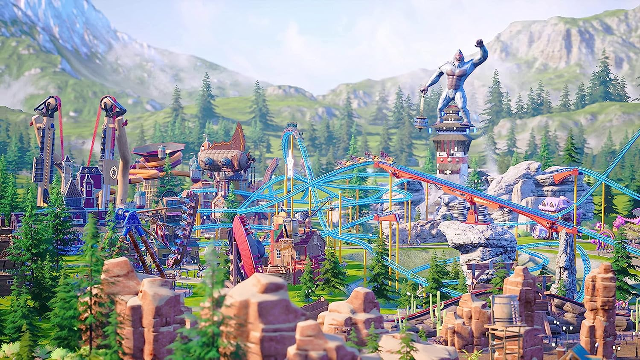 Park rozrywki z kolejkami górskimi, budynkami i gigantycznym posągiem. Góry w tle. Jasny, słoneczny dzień.