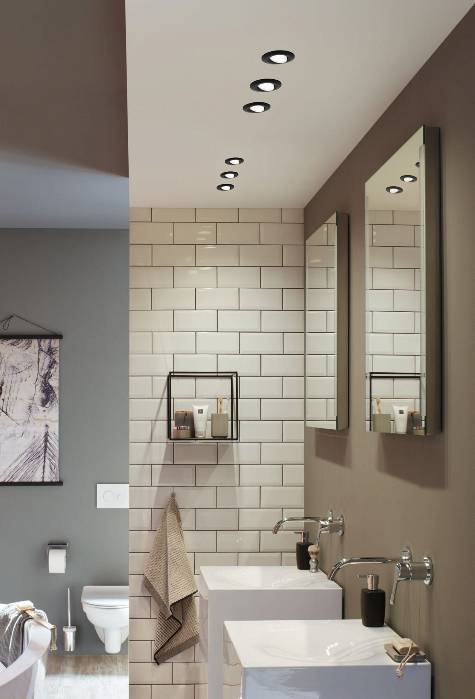 Nowoczesna łazienka z białymi kafelkowymi ścianami, lustrami, umywalkami i oświetleniem sufitowym.
