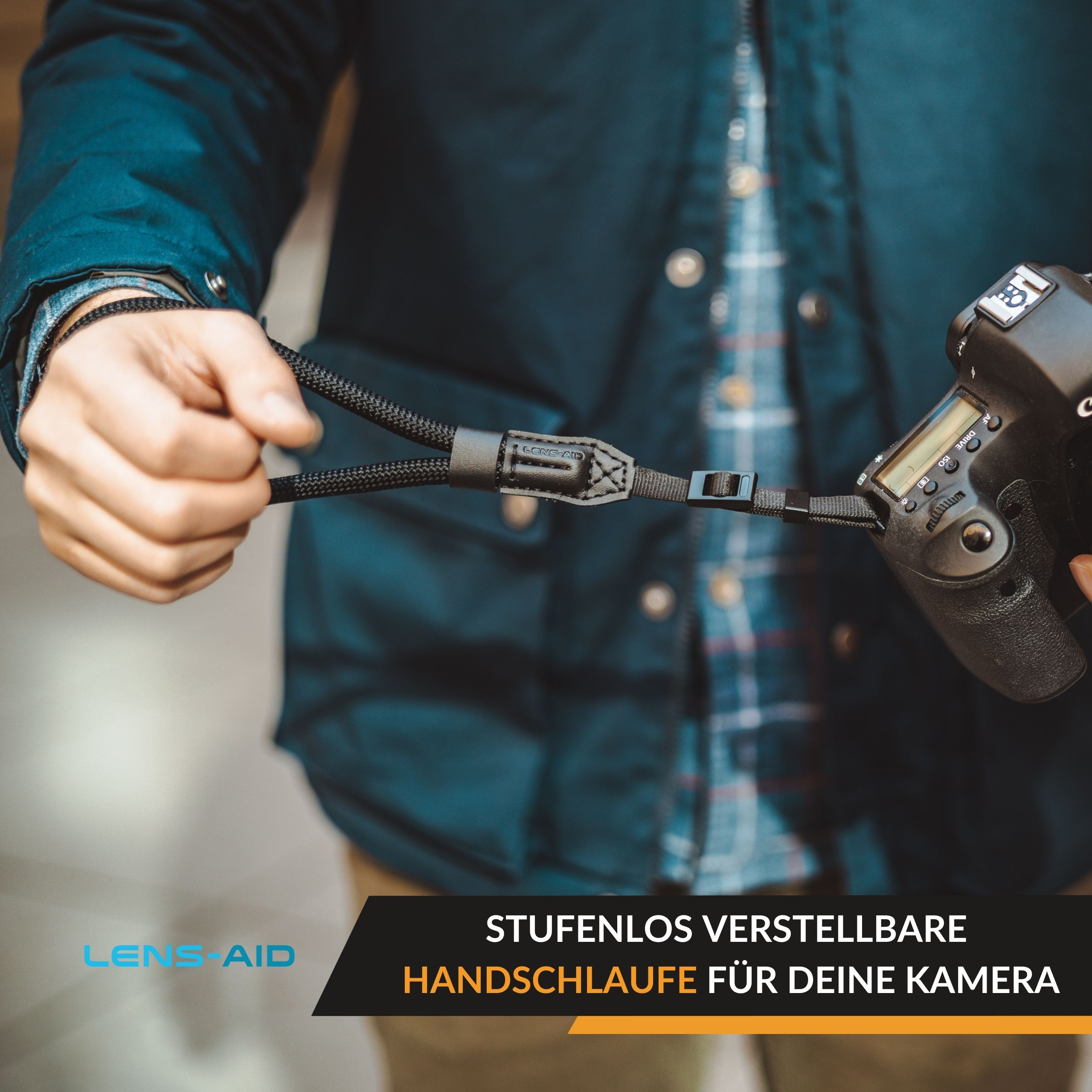 Eine Person hält eine Kamera mit einem Objektivriemen.