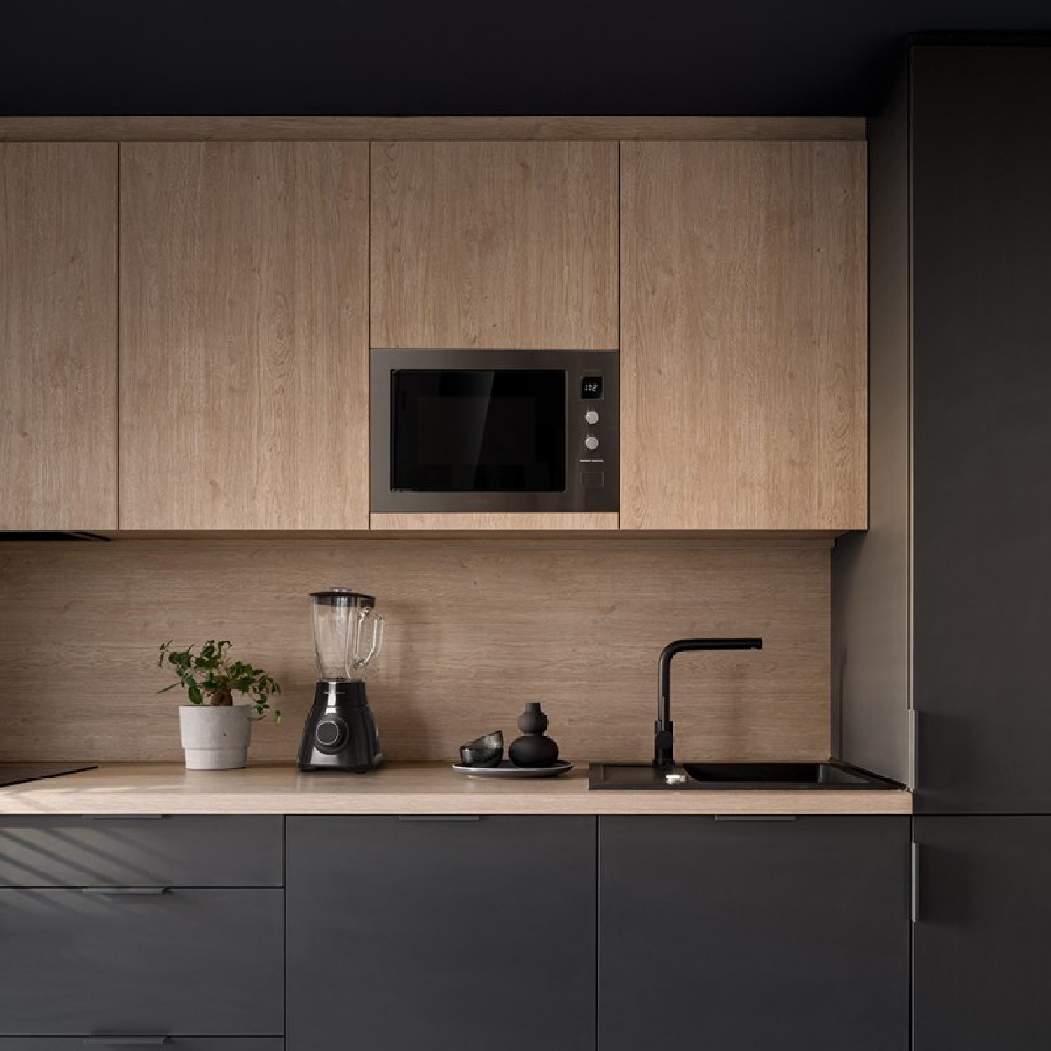 Kuchnia z drewnianymi szafkami, kuchenką mikrofalową i zlewem.