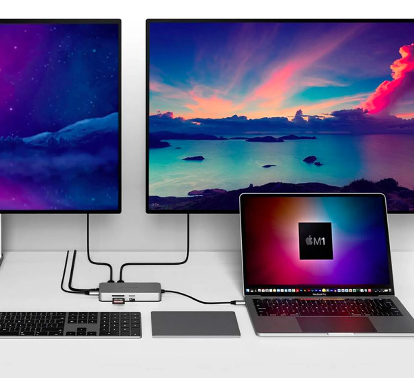 Monitores, teclado y portátil. Concentrador central. Muestra diferentes pantallas. Escritorio blanco.
