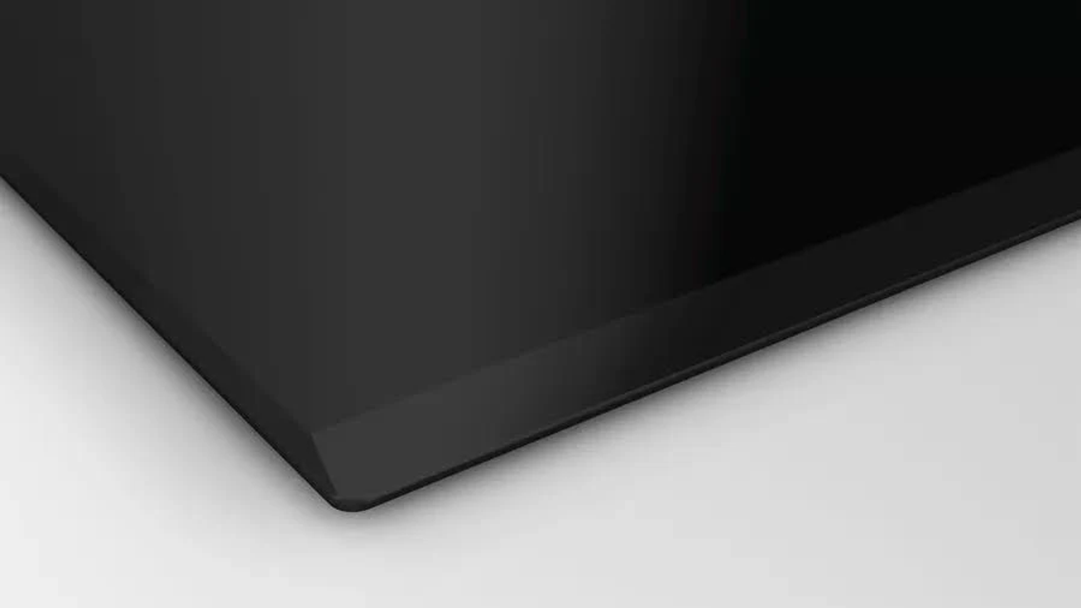 Zbliżenie na czarną płytę indukcyjną ze ściętą krawędzią.