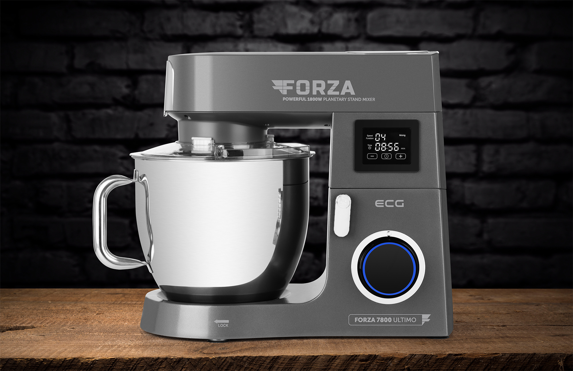Ein grauer Küchenmixer auf einer Holzoberfläche. Der Hintergrund ist eine dunkle Ziegelmauer.