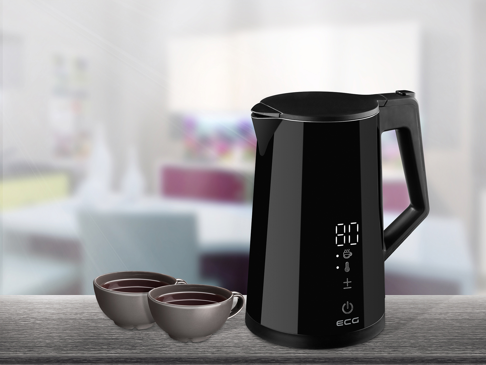 Czajnik elektryczny w kolorze czarnym z filiżankami na drewnianym stole, z rozmytym tłem.