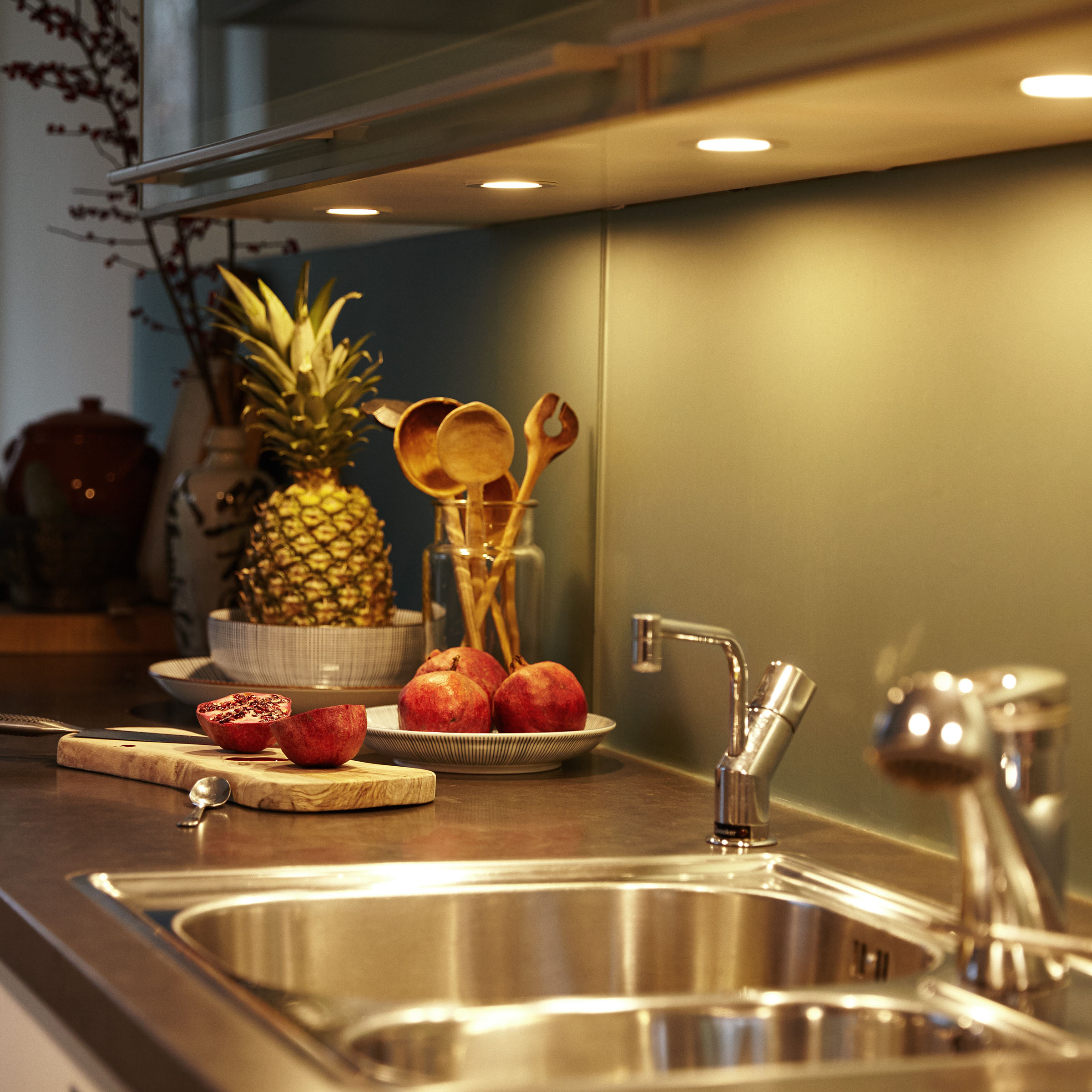 Scena kuchenna z ananasem, jabłkami i drewnianymi łyżkami w pobliżu zlewu.