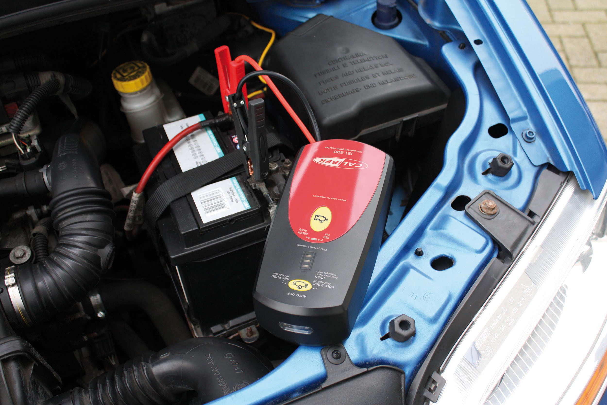 Motorraum mit Batterie und angeschlossenem Starthilfe-Gerät.