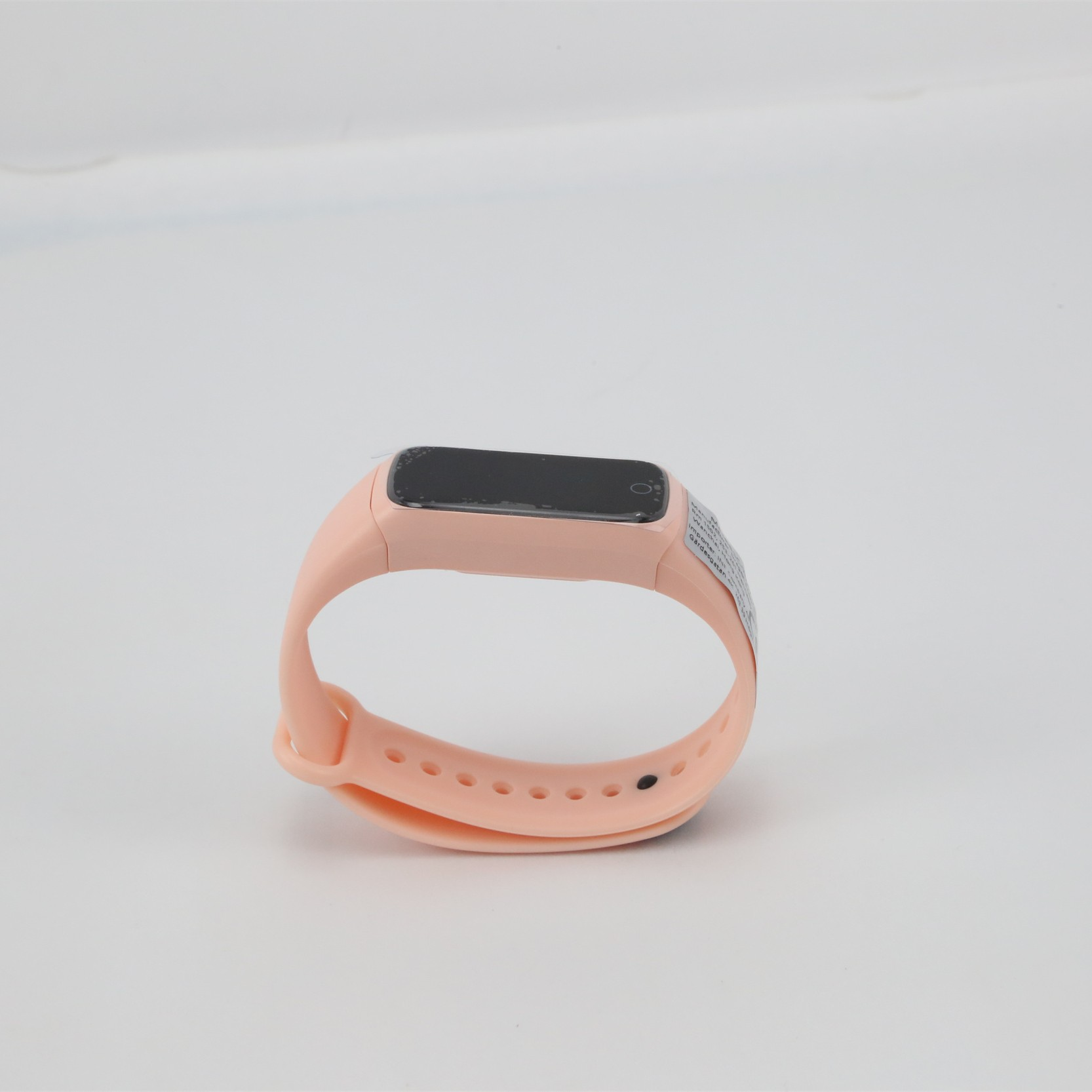 Różowy tracker fitness na białej powierzchni. Prosty design z małym ekranem.