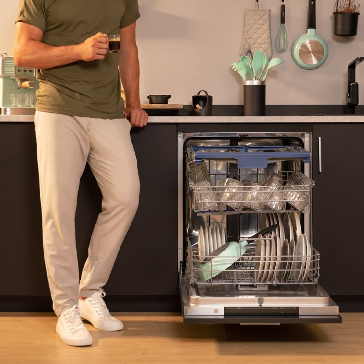 Uomo vicino a una lavastoviglie con porta aperta, ambiente cucina.
