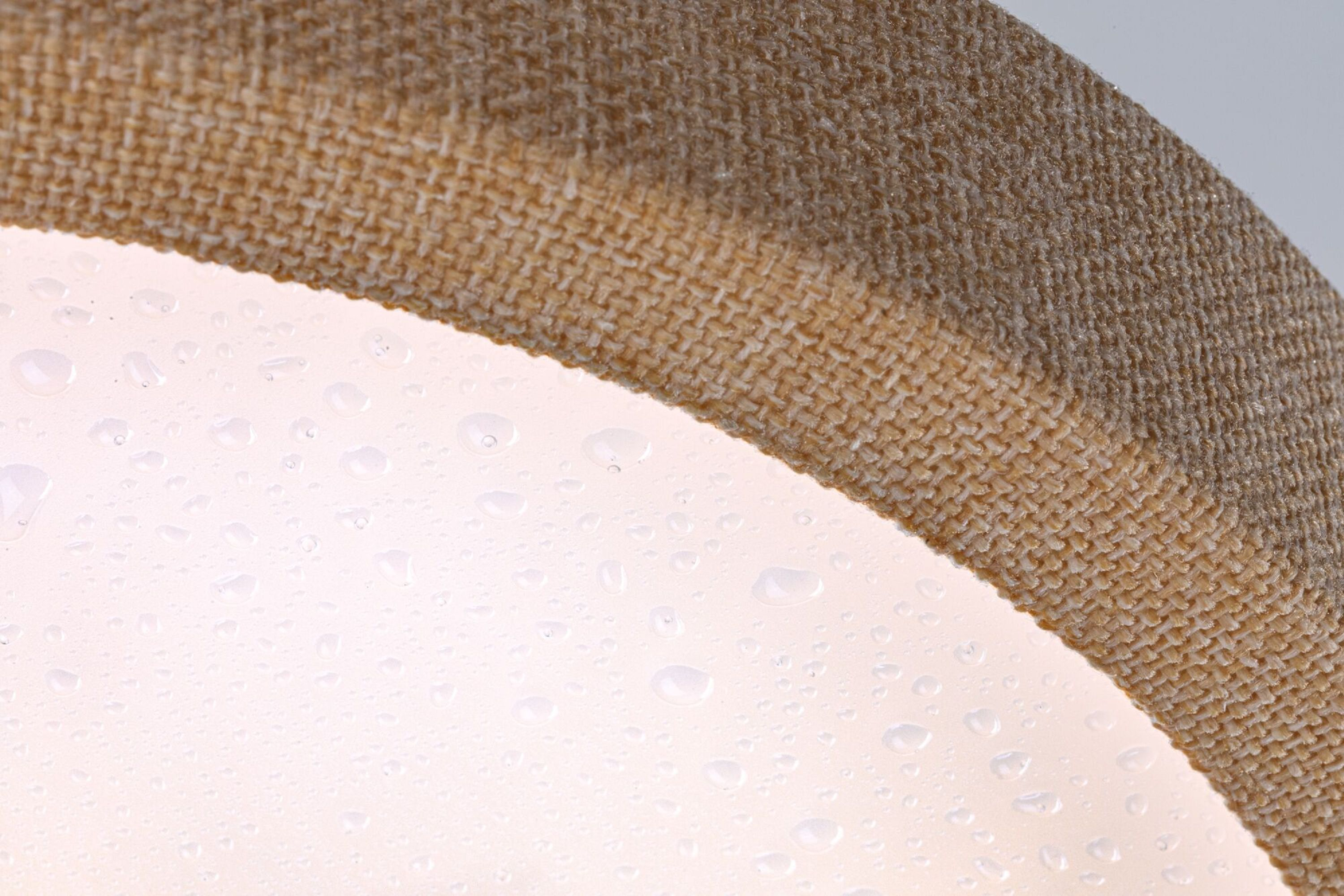 Zbliżenie lampy z kroplami wody na podświetlanej powierzchni.