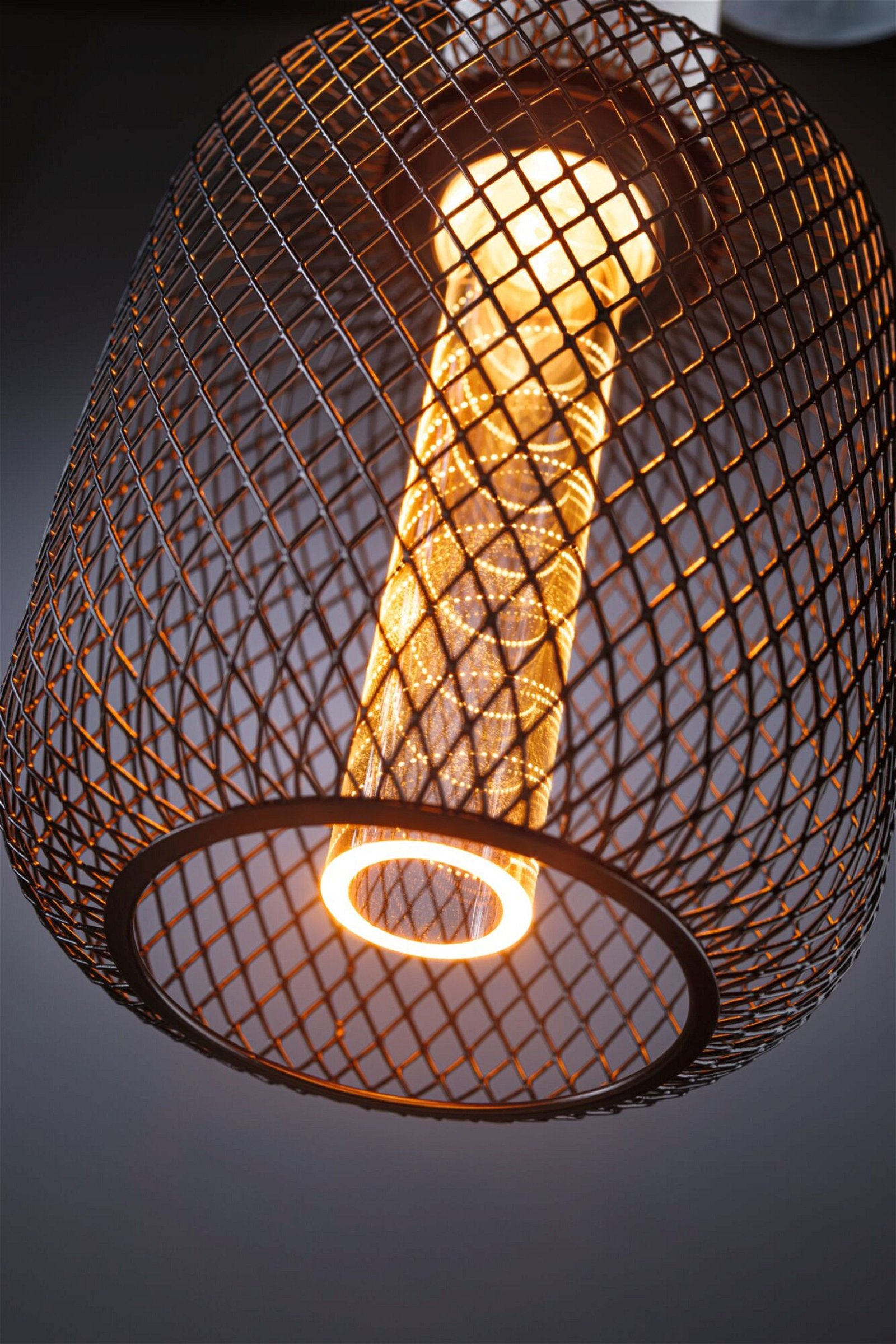 Czarna metalowa lampa wisząca w kształcie klatki z podłużną, świecącą żarówką w środku.