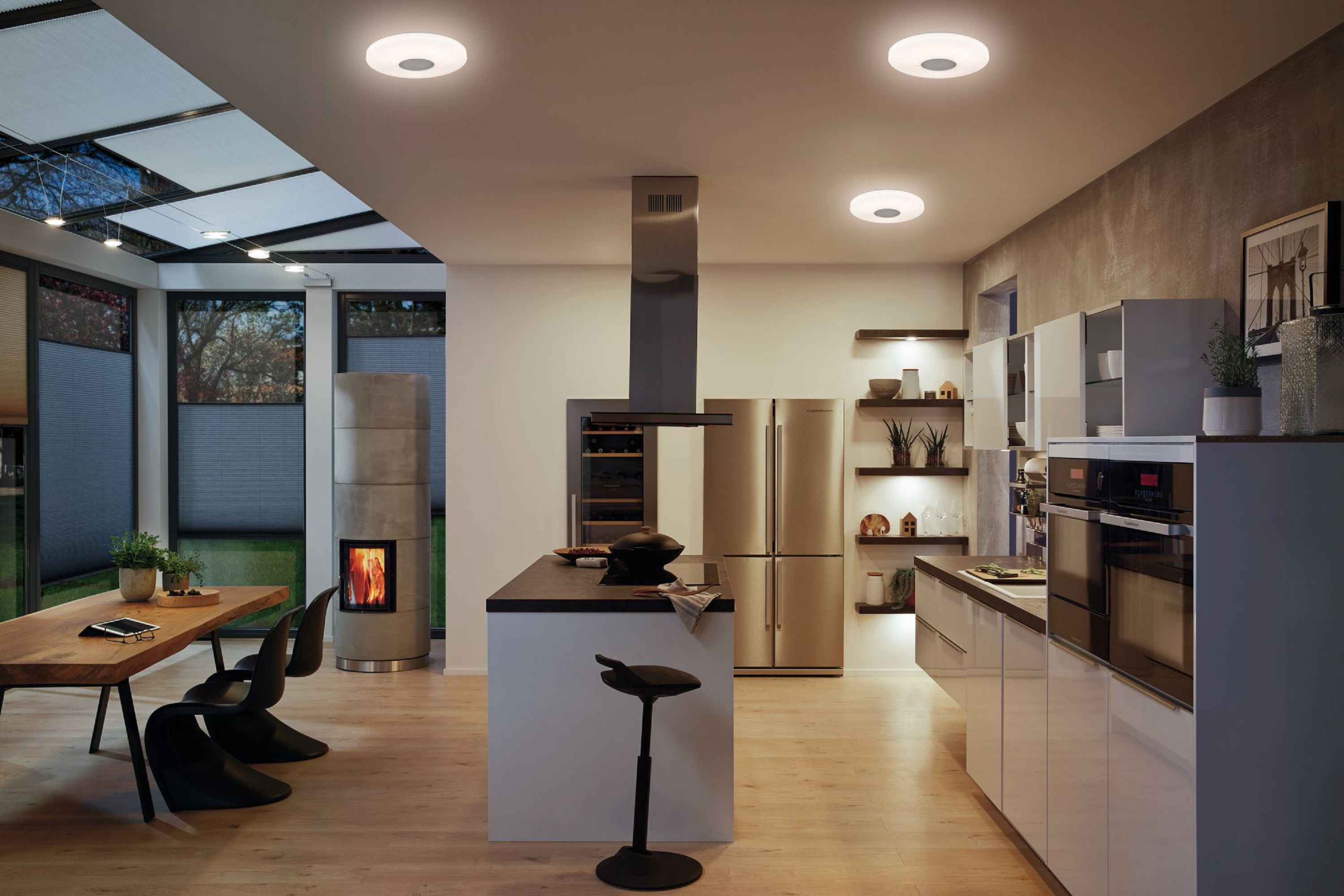 Nowoczesna kuchnia z kilkoma lampami sufitowymi. Jest kominek i czarna wyspa.