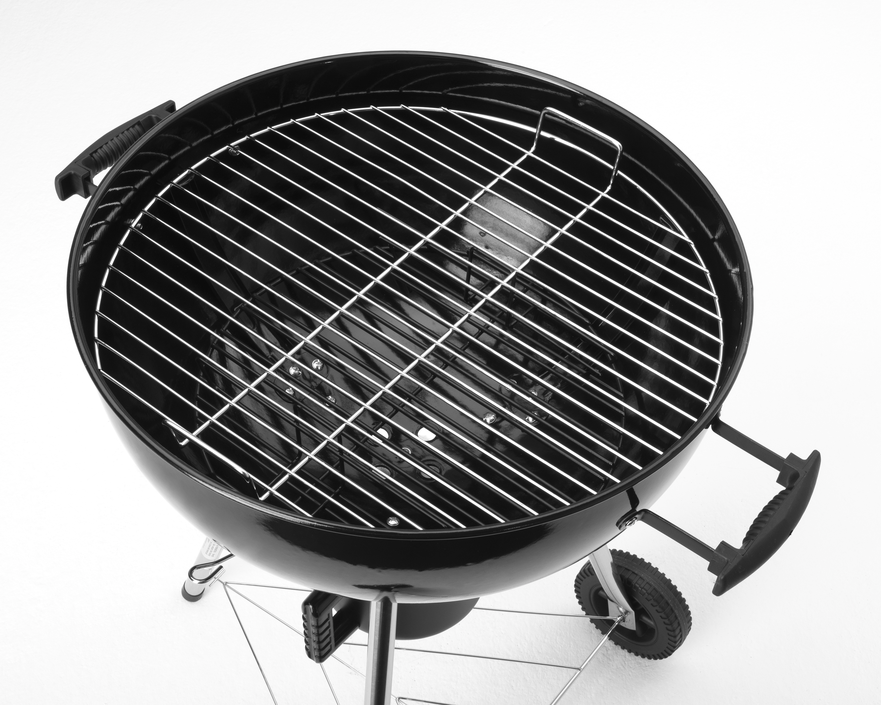 Czarny, okrągły grill z metalowym rusztem. Białe tło.