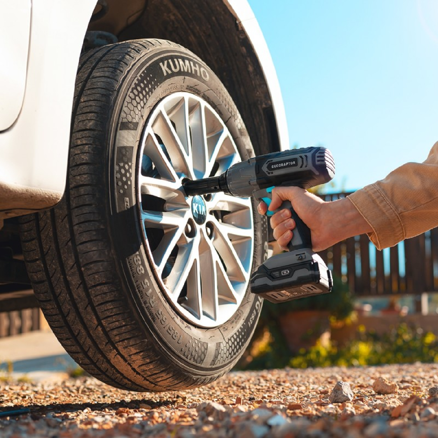 Osoba używa bezprzewodowego klucza udarowego do demontażu opony z samochodu.
