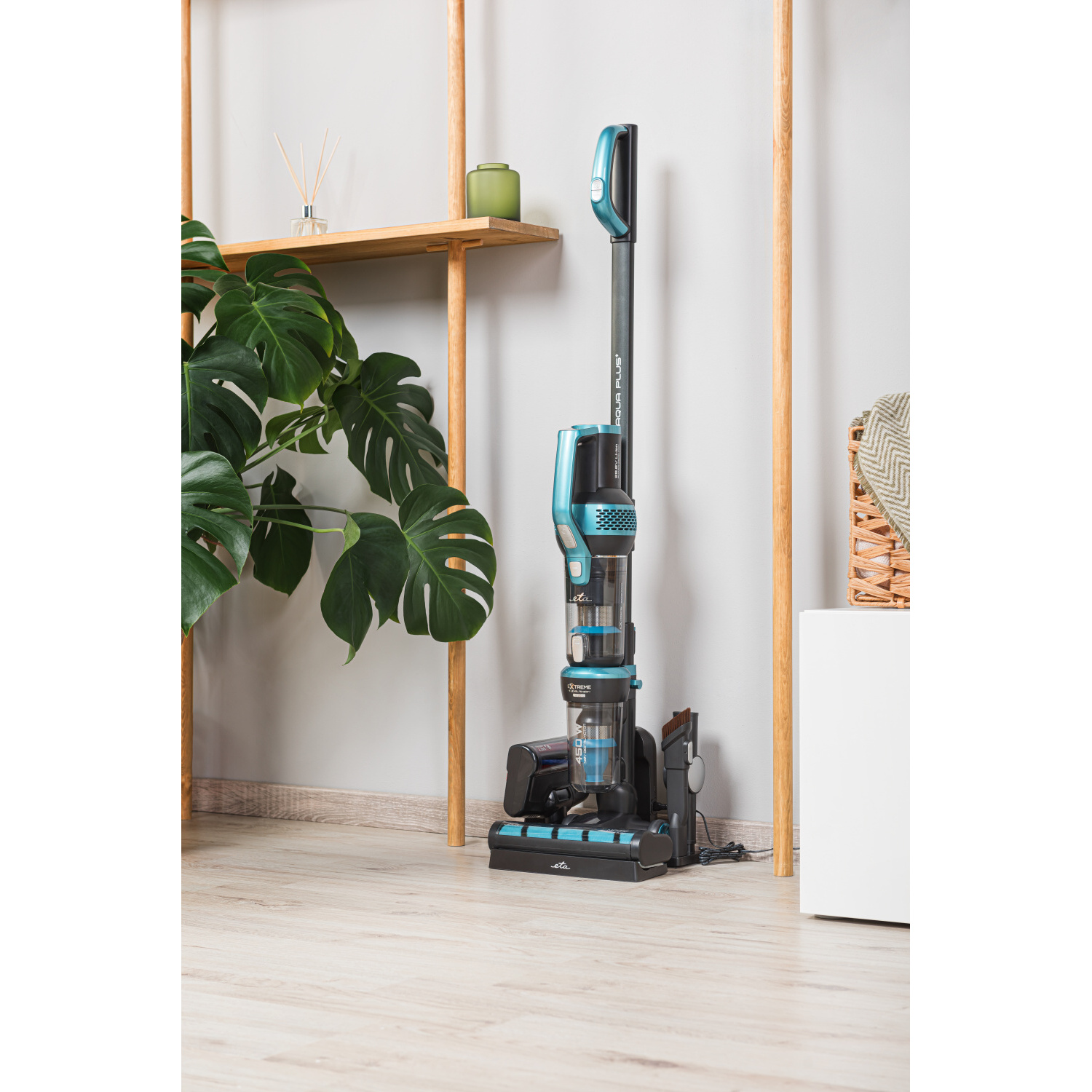 Aufrechter Staubsauger in einem Raum mit Pflanze und Holzregalen. Heller Hintergrund.