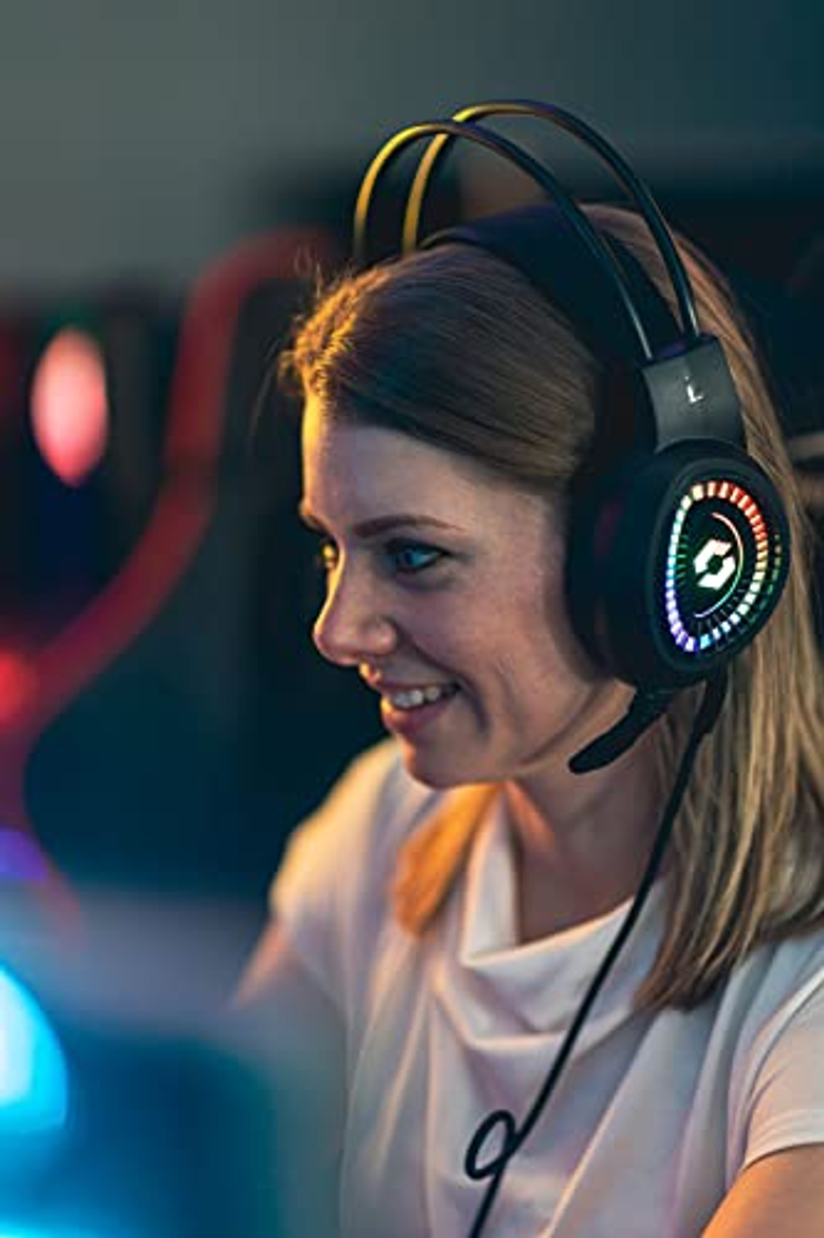 Una donna sorridente con cuffie da gioco, che gioca a un videogioco.