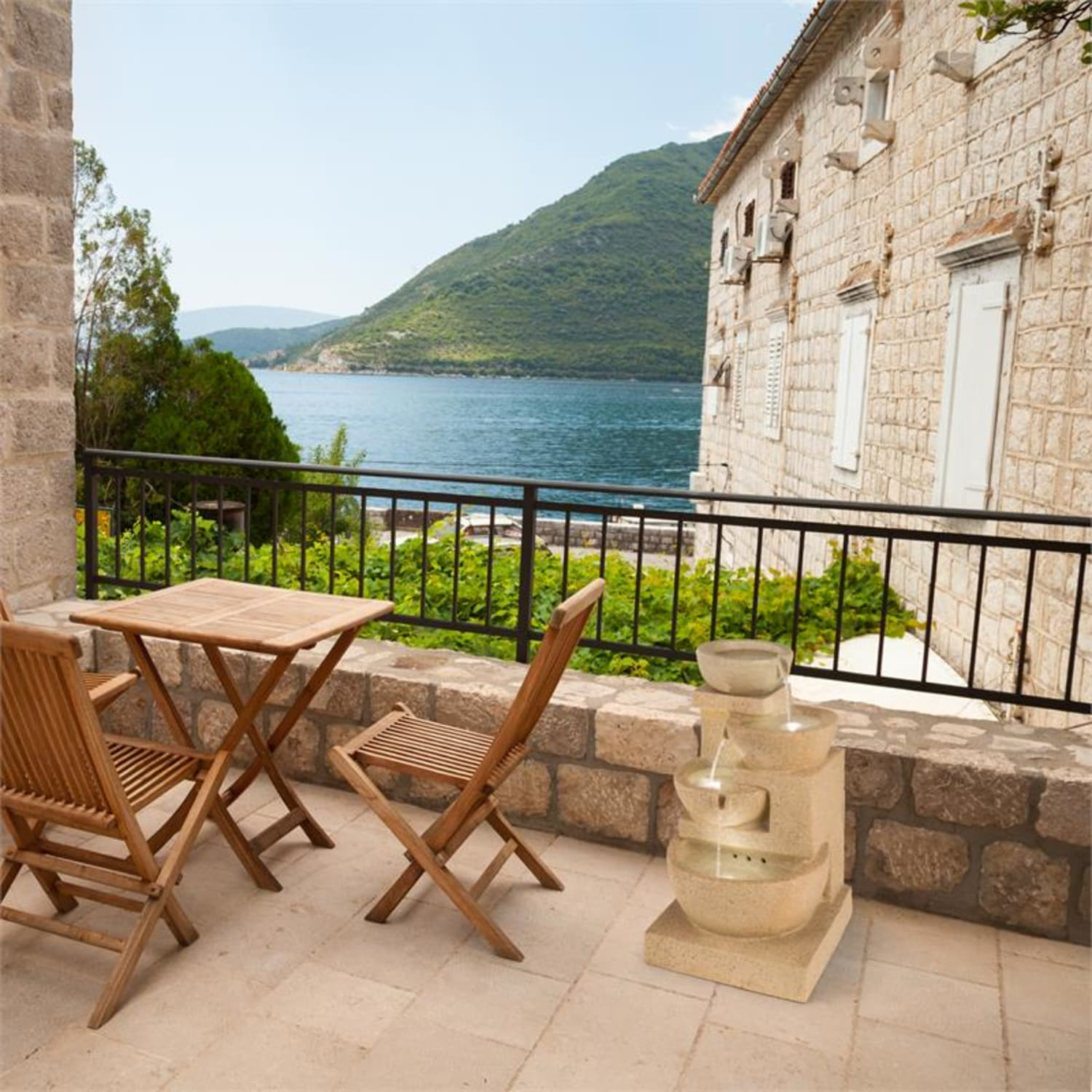 Eine Terrasse mit Tisch, Stühlen und Brunnen mit Blick aufs Meer.