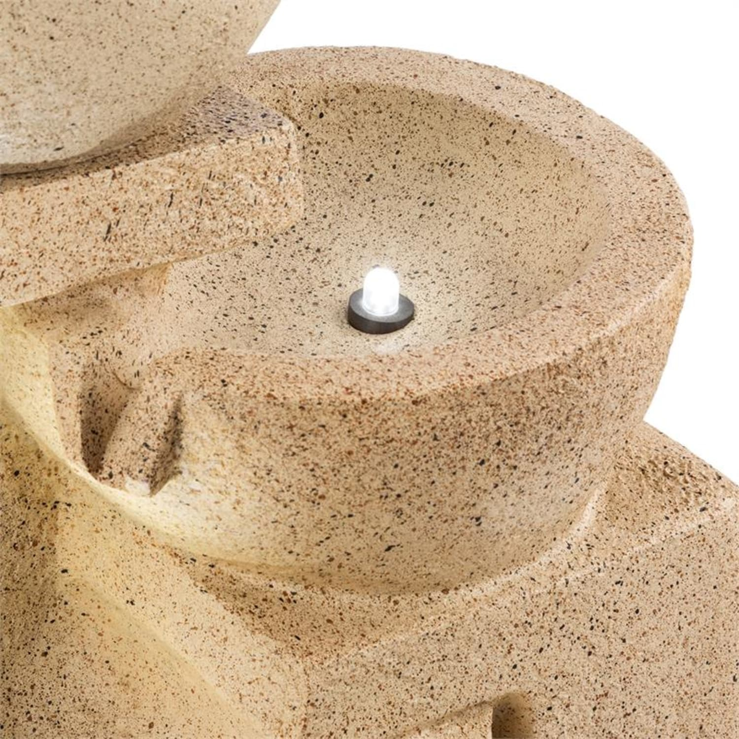 Beige Stein-Wasserbrunnen mit einem kleinen Licht in der Schüssel.