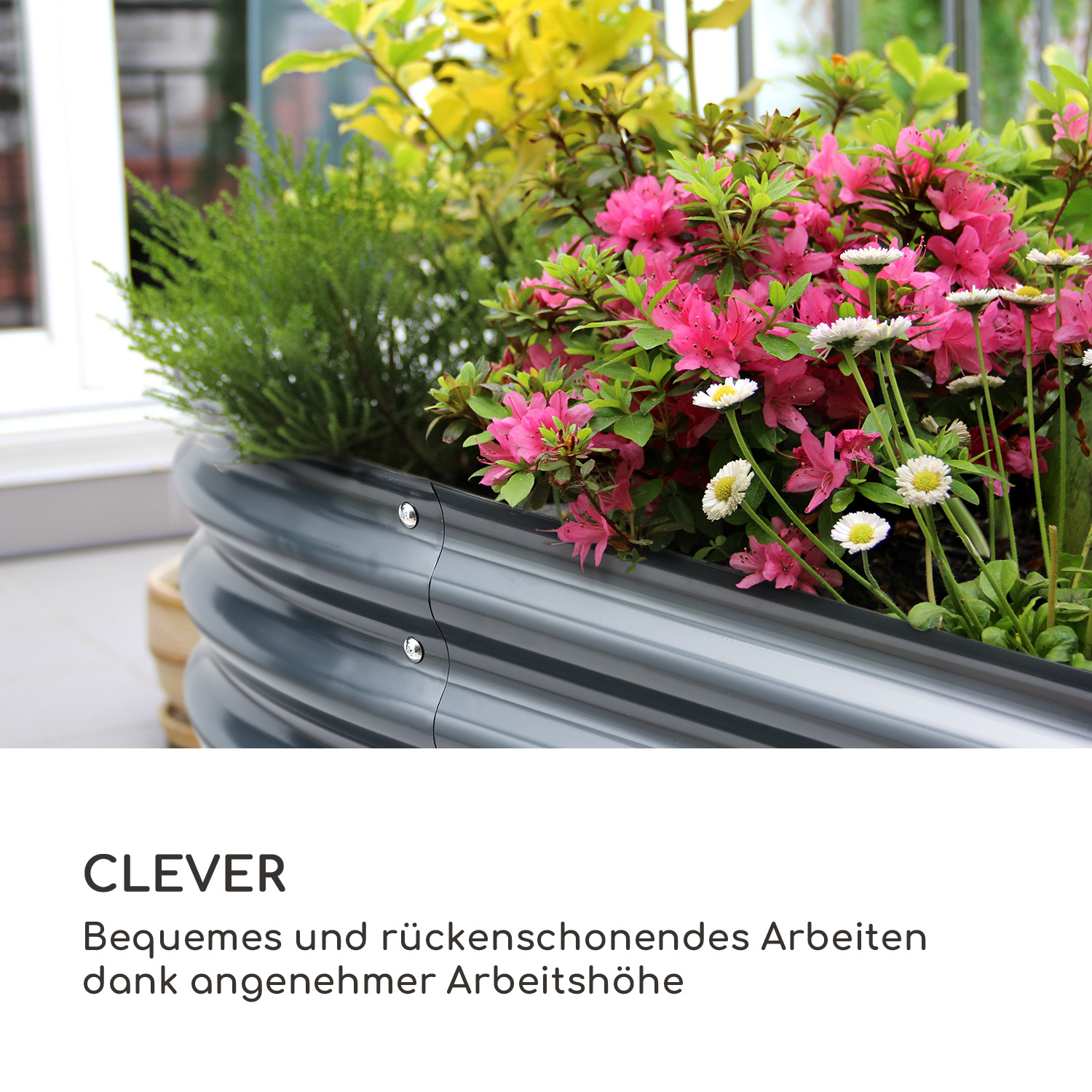 Grauer Metall-Pflanzkübel mit rosa und weißen Blumen, mit Text in deutscher Sprache.