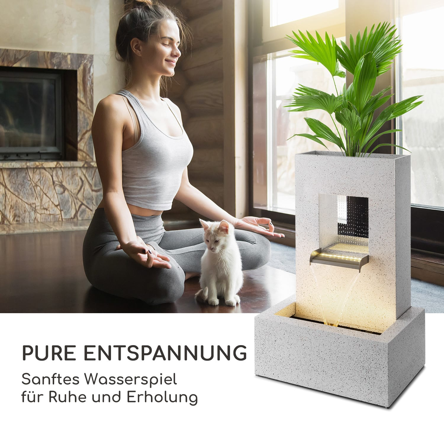 Eine Frau meditiert in der Nähe eines Brunnens mit einer Pflanze und einer Katze. Das Wasserspiel ist beleuchtet.