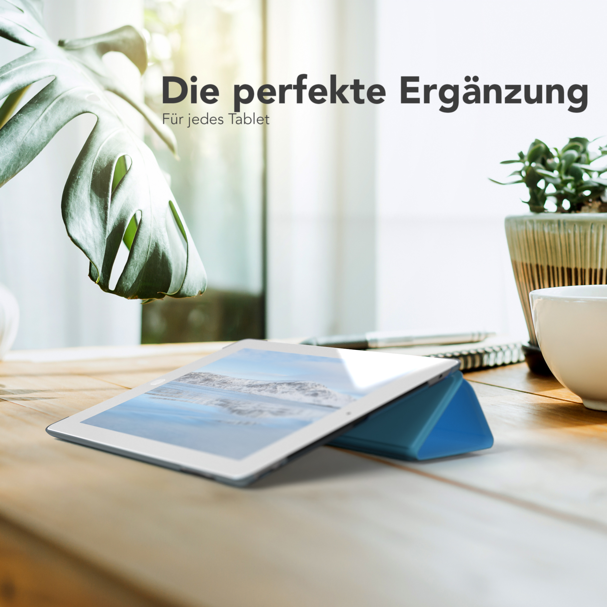 Ein Tablet mit blauem Gehäuse auf einem Holztisch. Eine Pflanze und eine Tasse sind im Hintergrund.