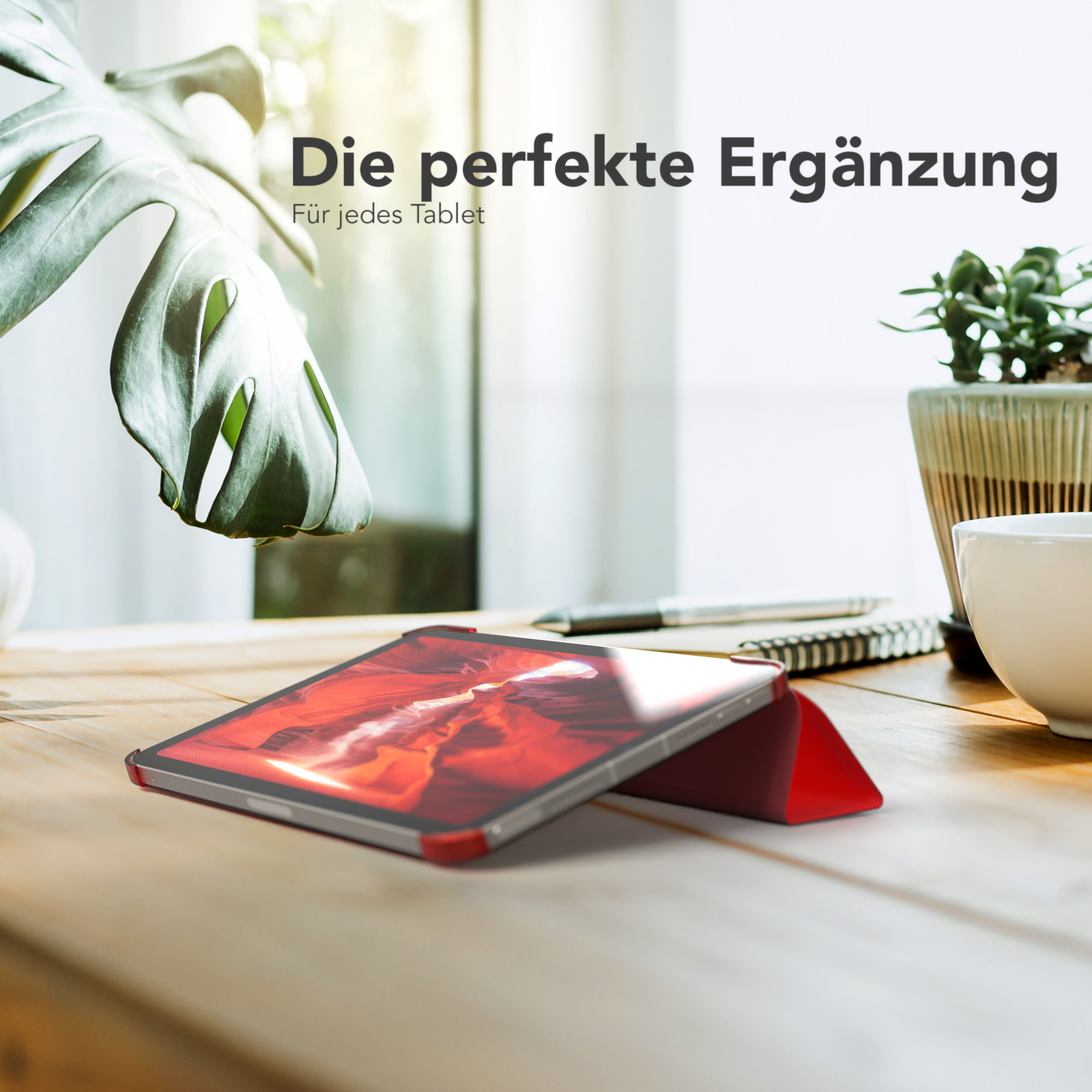 Tablet in roter Hülle auf einem Holztisch mit Pflanze und Tasse.