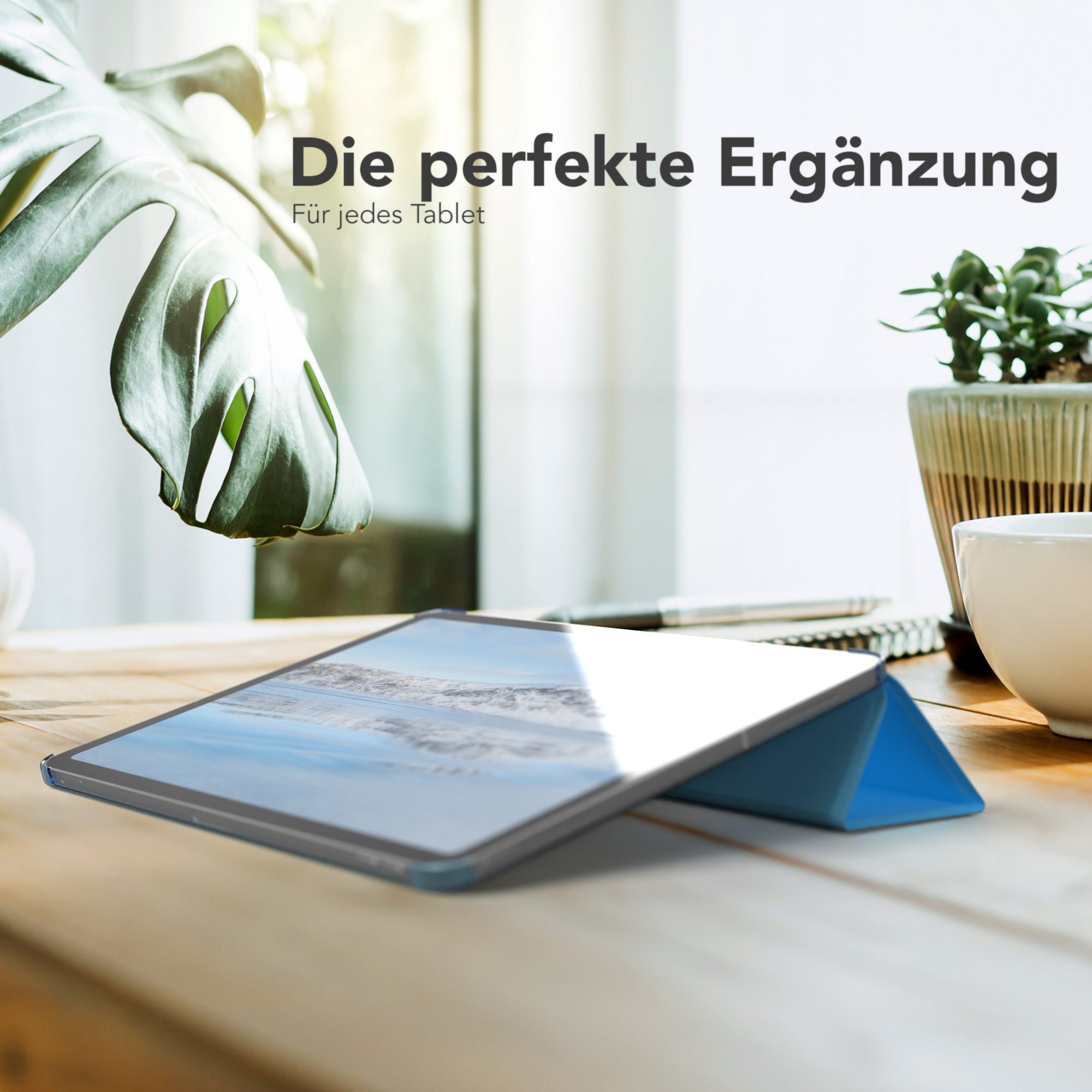 Tablet auf einem Holztisch in einem blauen Case. Eine Pflanze und eine Tasse sind im Hintergrund.