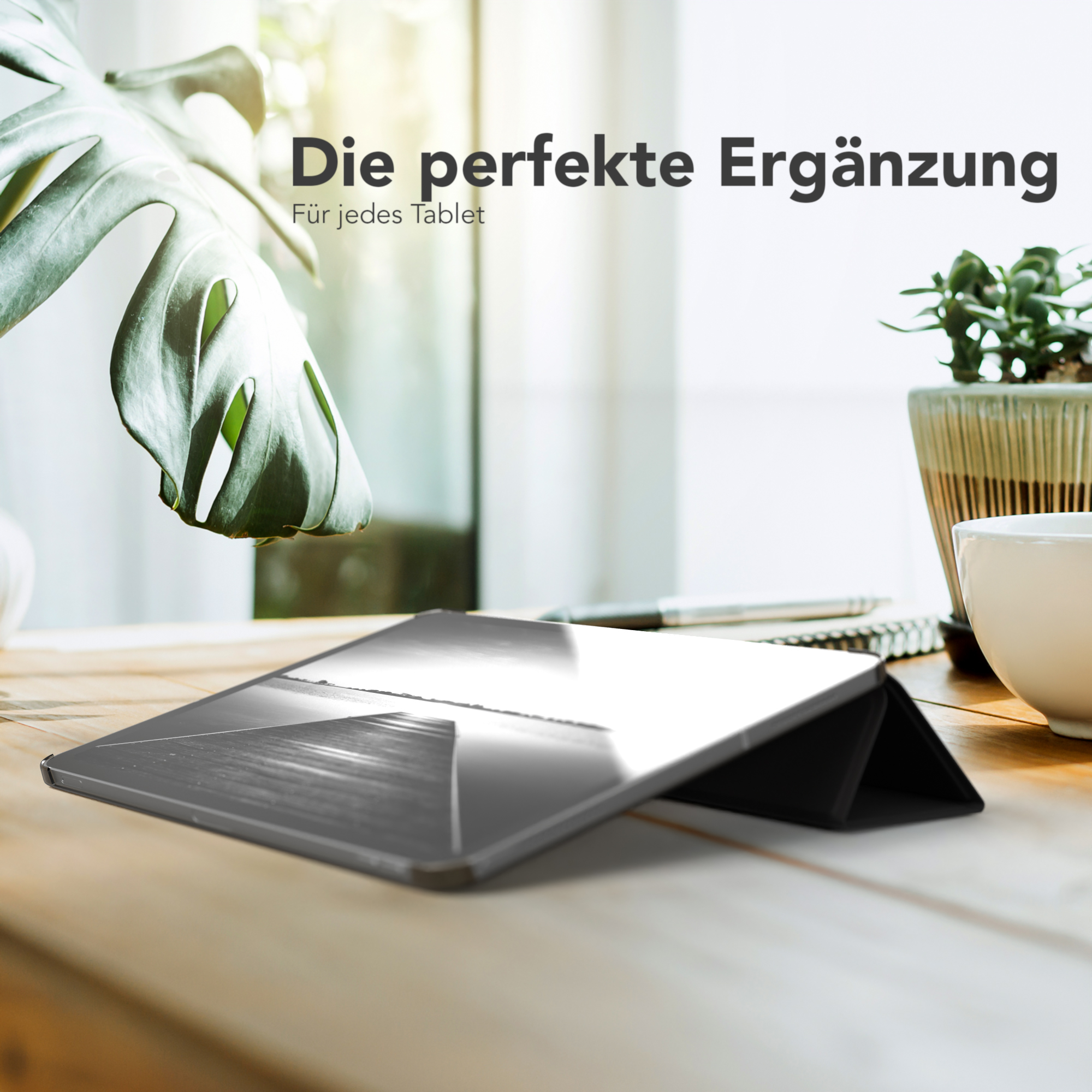 Tablet und Hülle auf Holztisch mit Pflanze und Tasse.