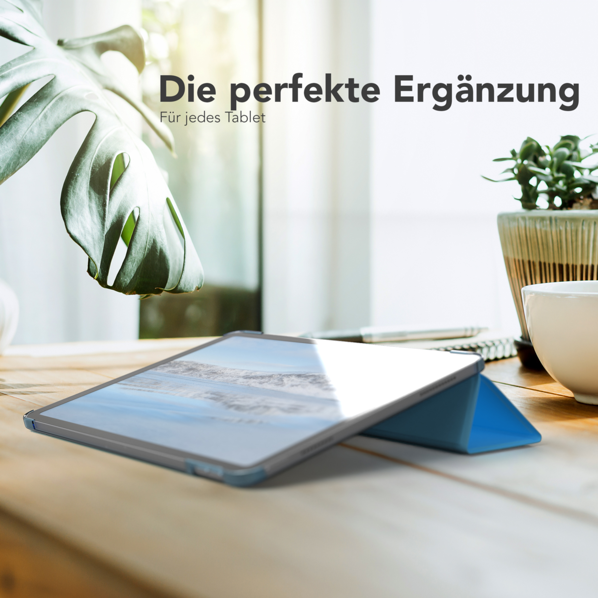 Tablet mit blauer Hülle, das eine Landschaft auf dem Bildschirm zeigt. Es steht auf einem Holztisch neben einer Pflanze.