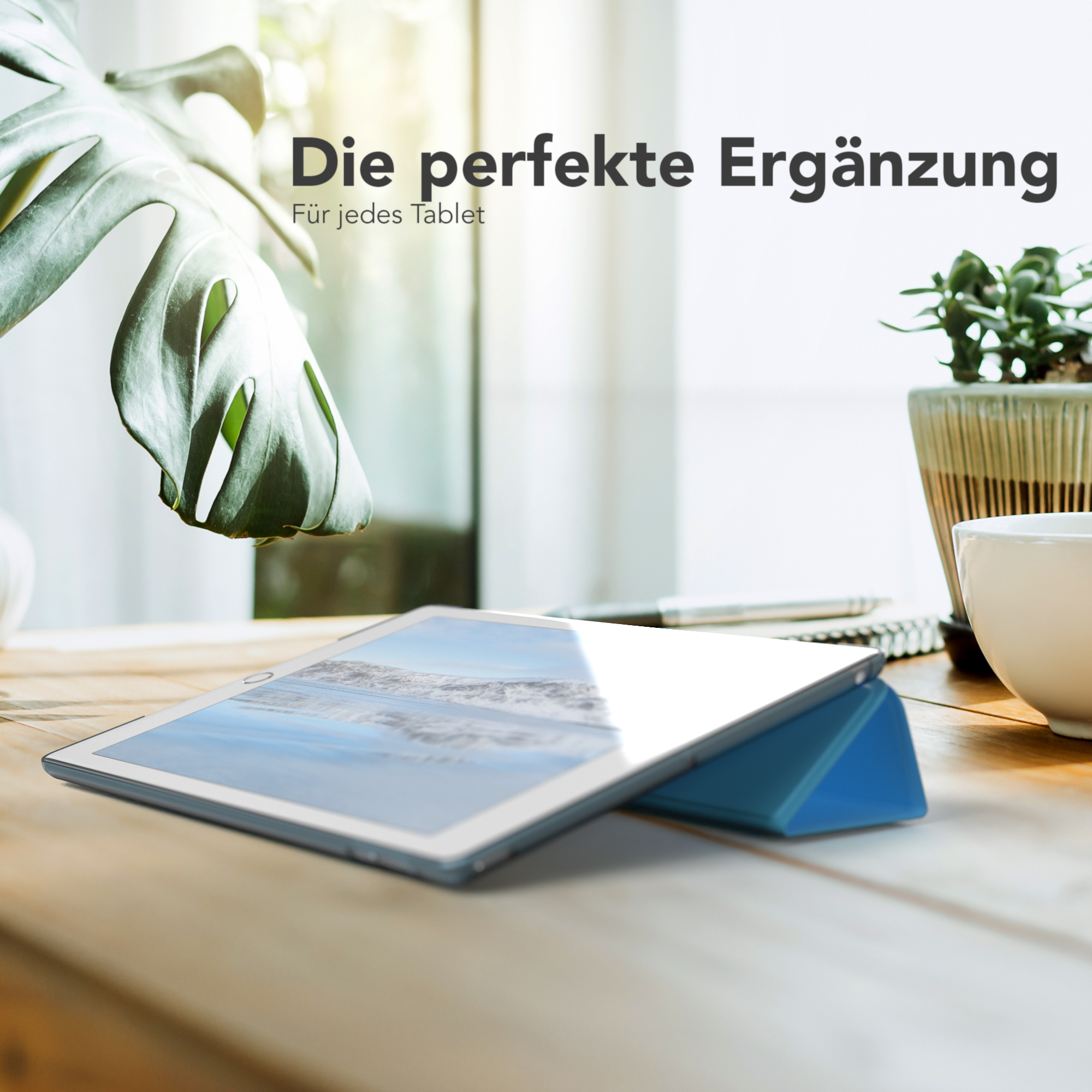 Ein Tablet auf einem blauen Ständer auf einem Holztisch, mit Pflanze und Tasse.