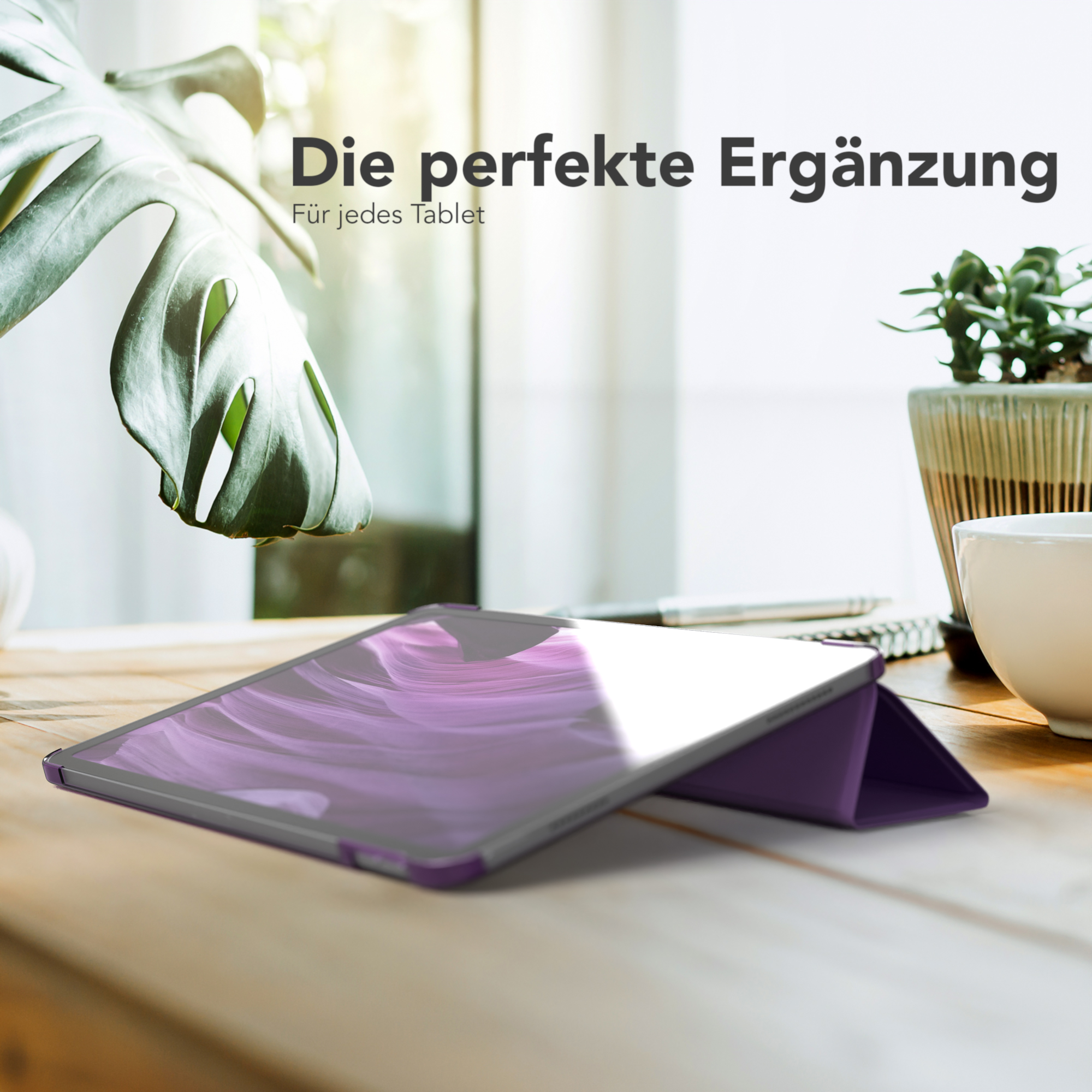 Ein Tablet mit lila Hülle liegt auf einem Holztisch. Im Hintergrund sind eine Pflanze und eine Tasse zu sehen.