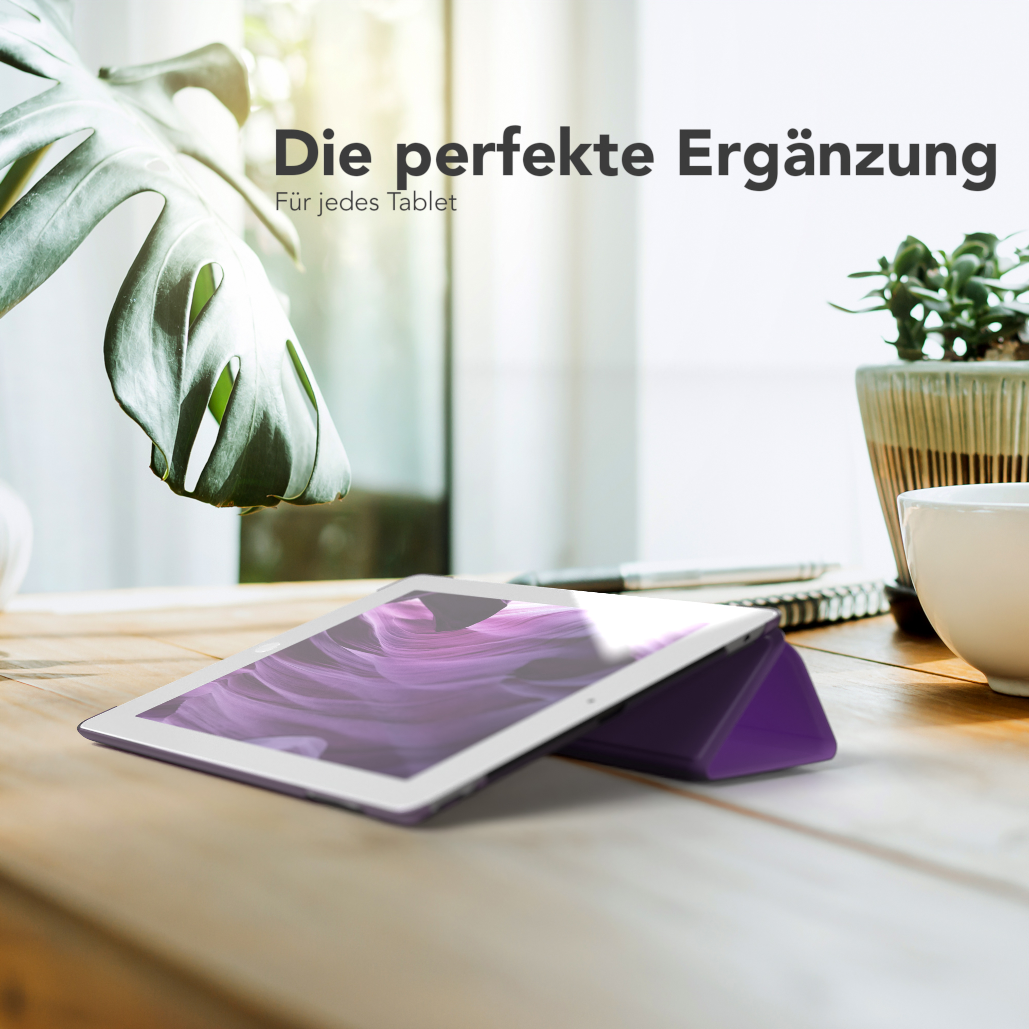 Ein Tablet und eine Hülle auf einem Holztisch mit Pflanze und Tasse.
