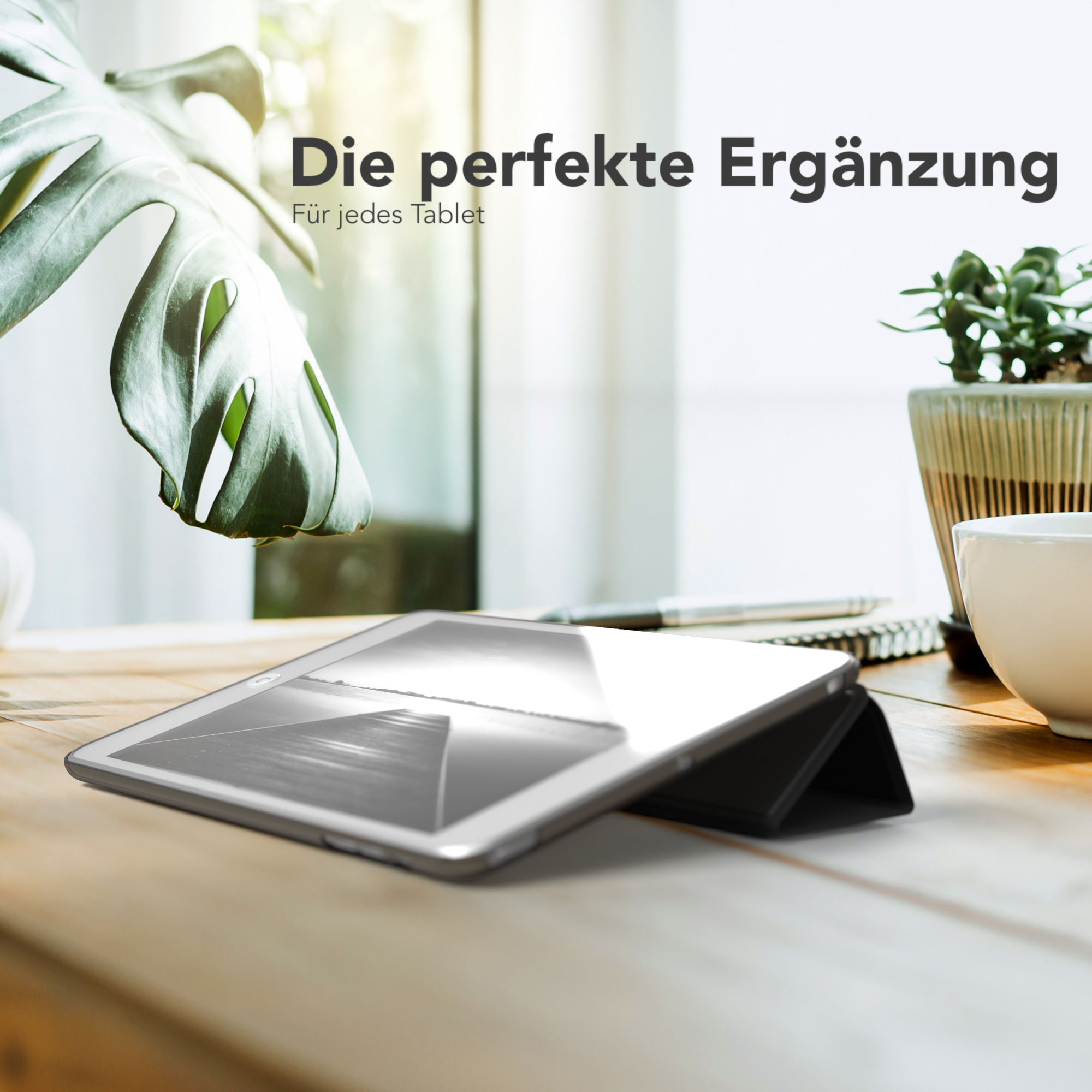 Tablet auf einem Holztisch mit einer Pflanze und einer Kaffeetasse. Das Tablet ist in einer Schutzhülle.