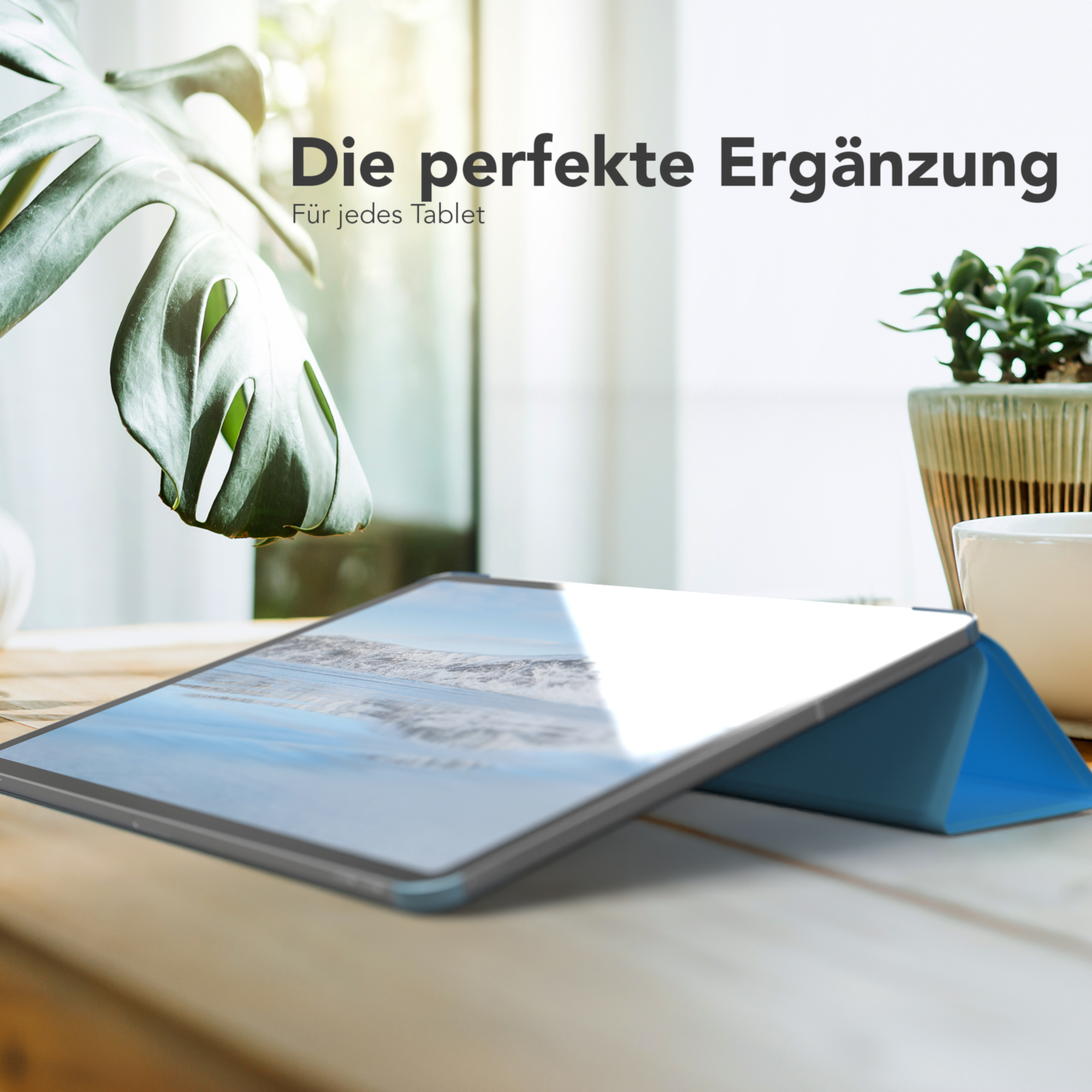 iPad auf einem Holztisch mit blauem Case, Pflanze und Tasse.