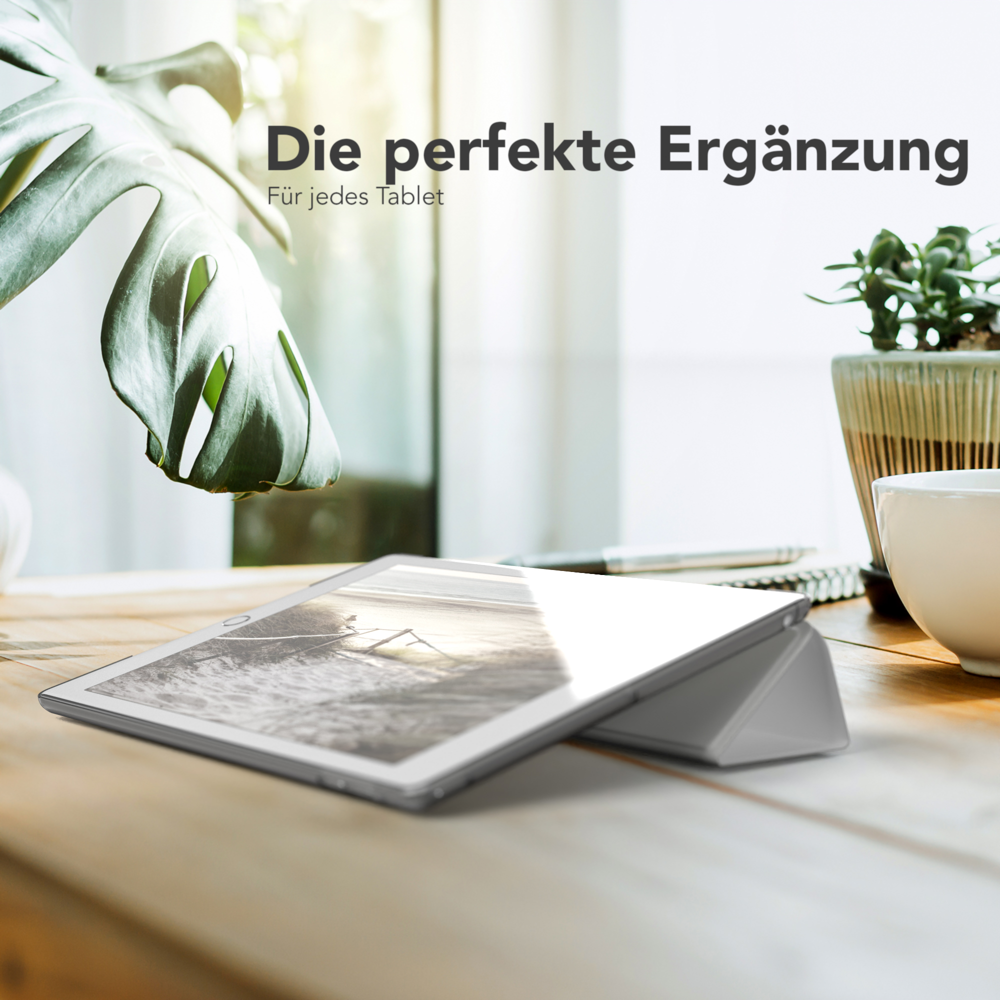Tablet in grauem Gehäuse auf Holztisch, Pflanze im Hintergrund. Text: 'Die perfekte Ergänzung'.